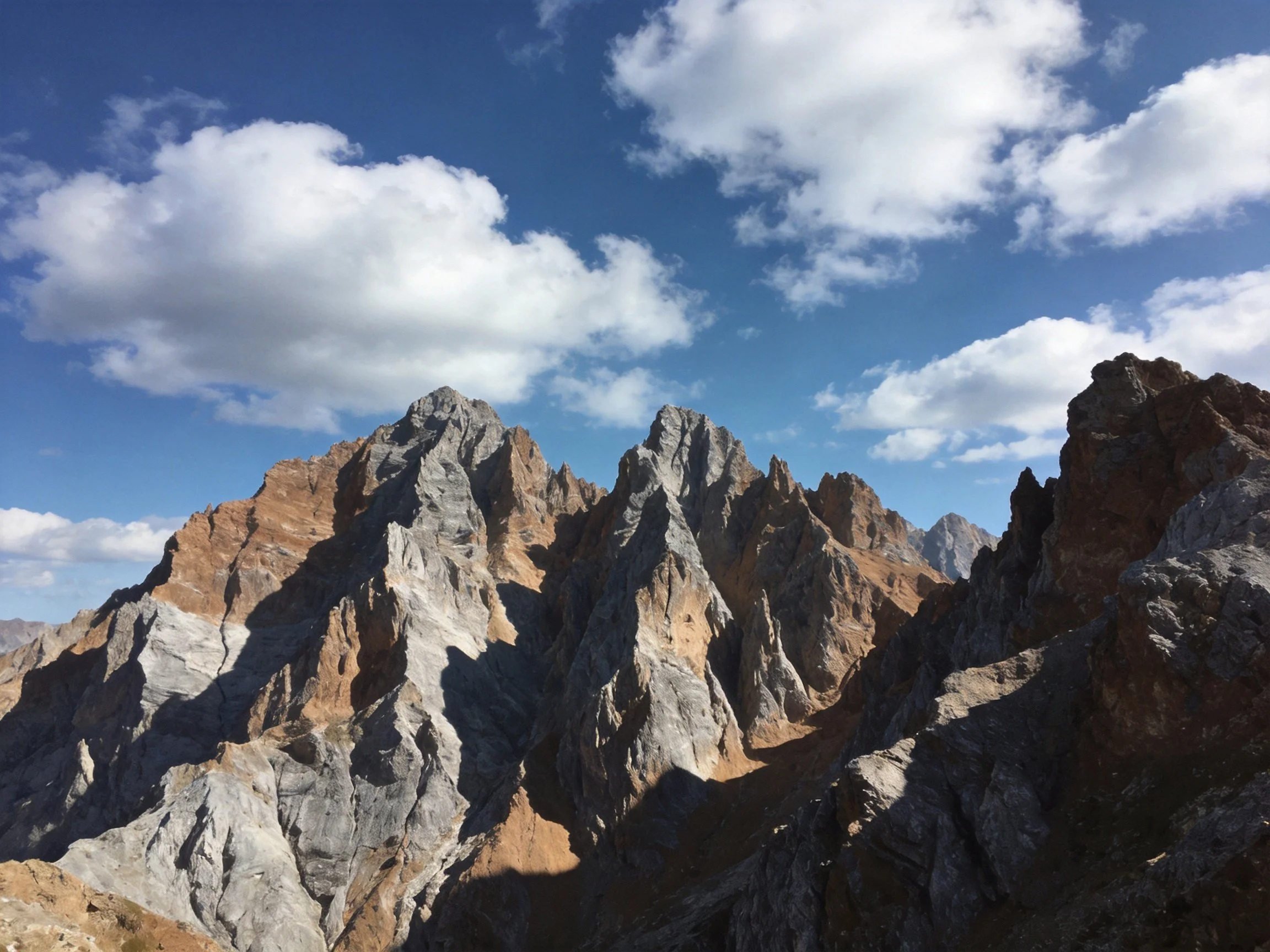 Rugged mountain peaks with earthy rock hues under a clear blue sky