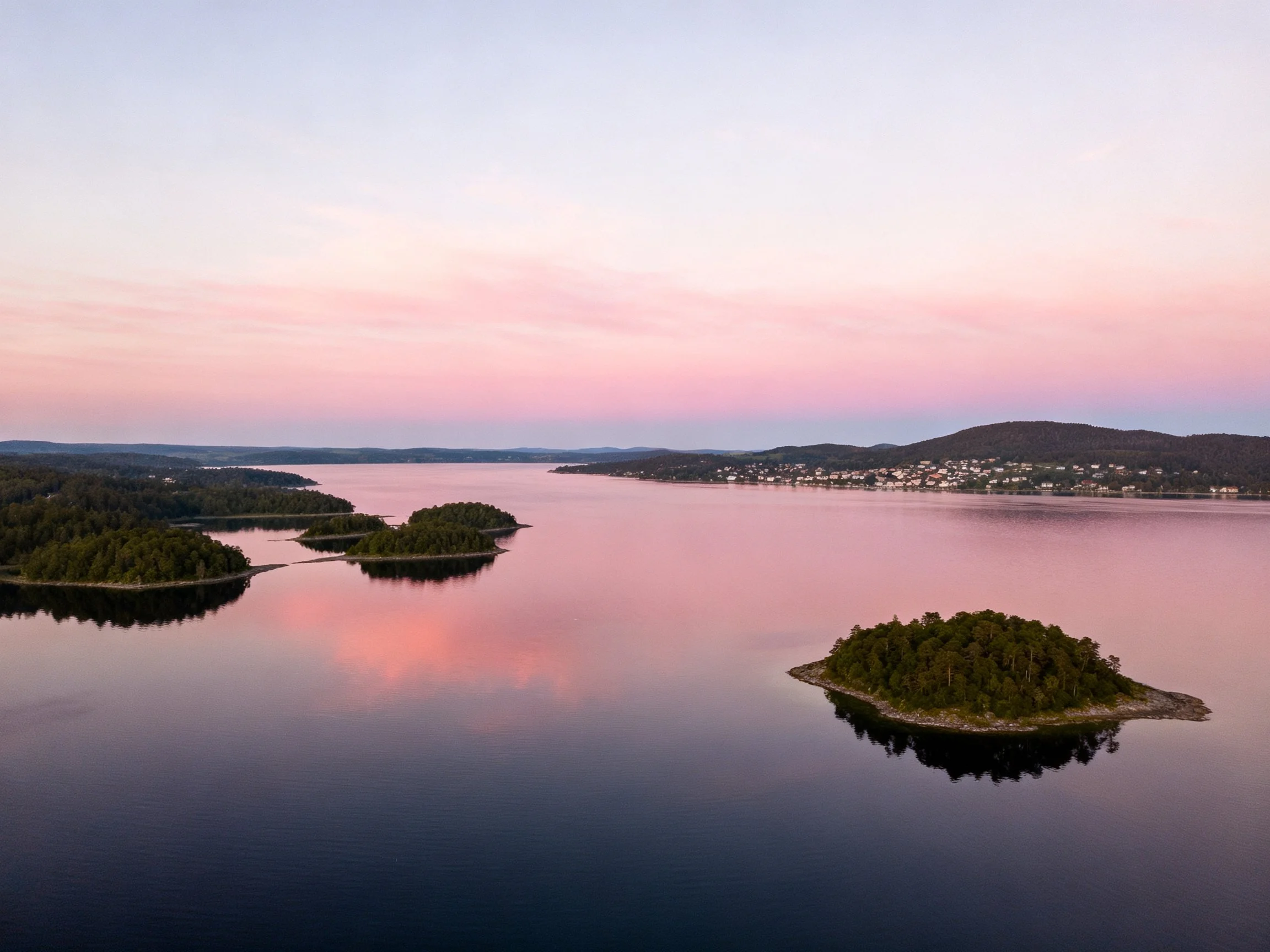 Serene waterway with forested islands and pink sunset
