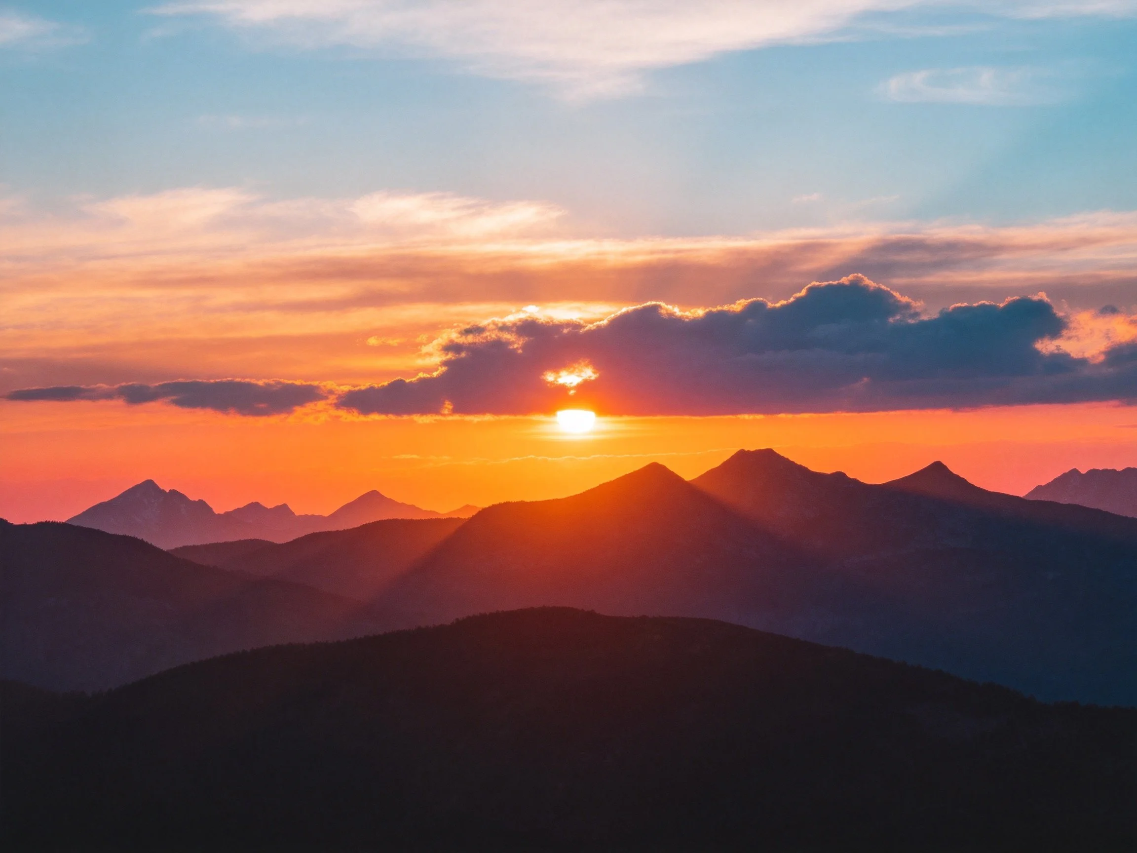 Silhouetted mountain ranges under a vibrant sunset sky