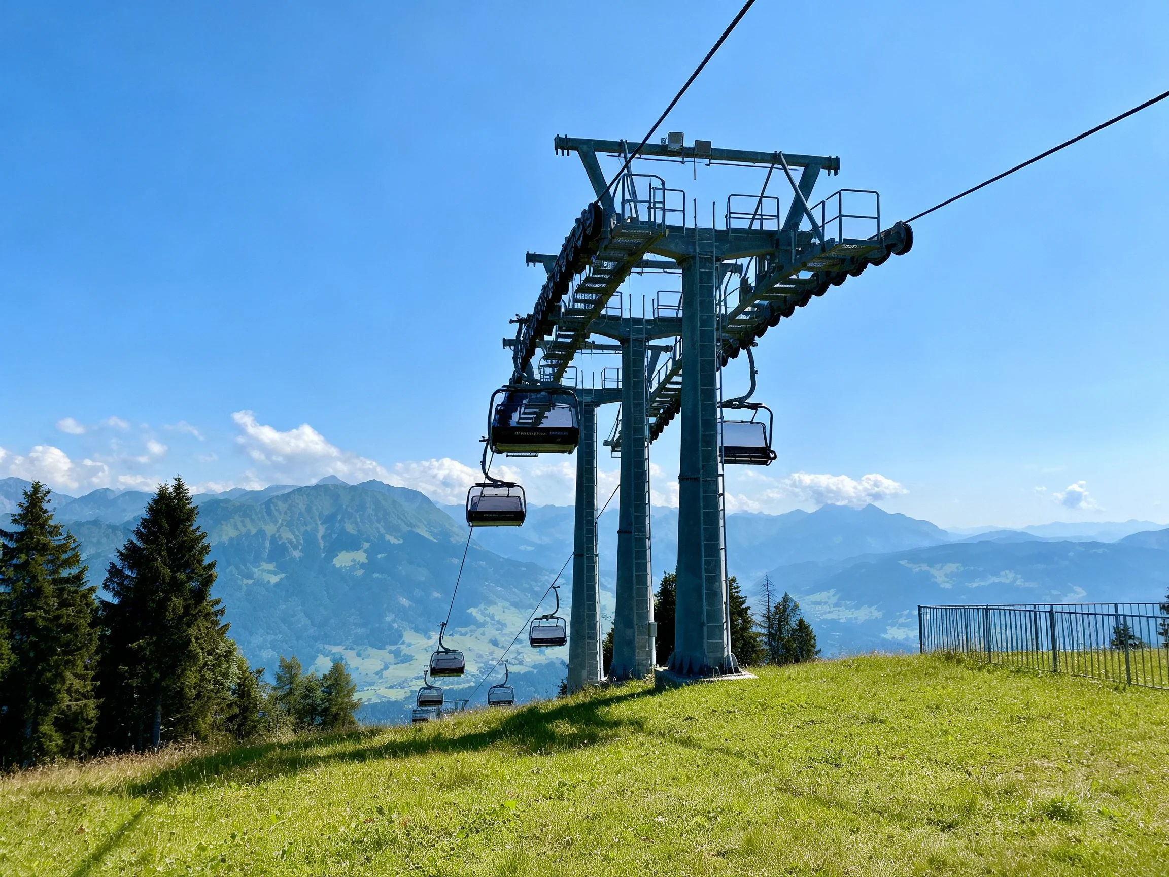 Ski lift station with mountainous backdrop and green meadow