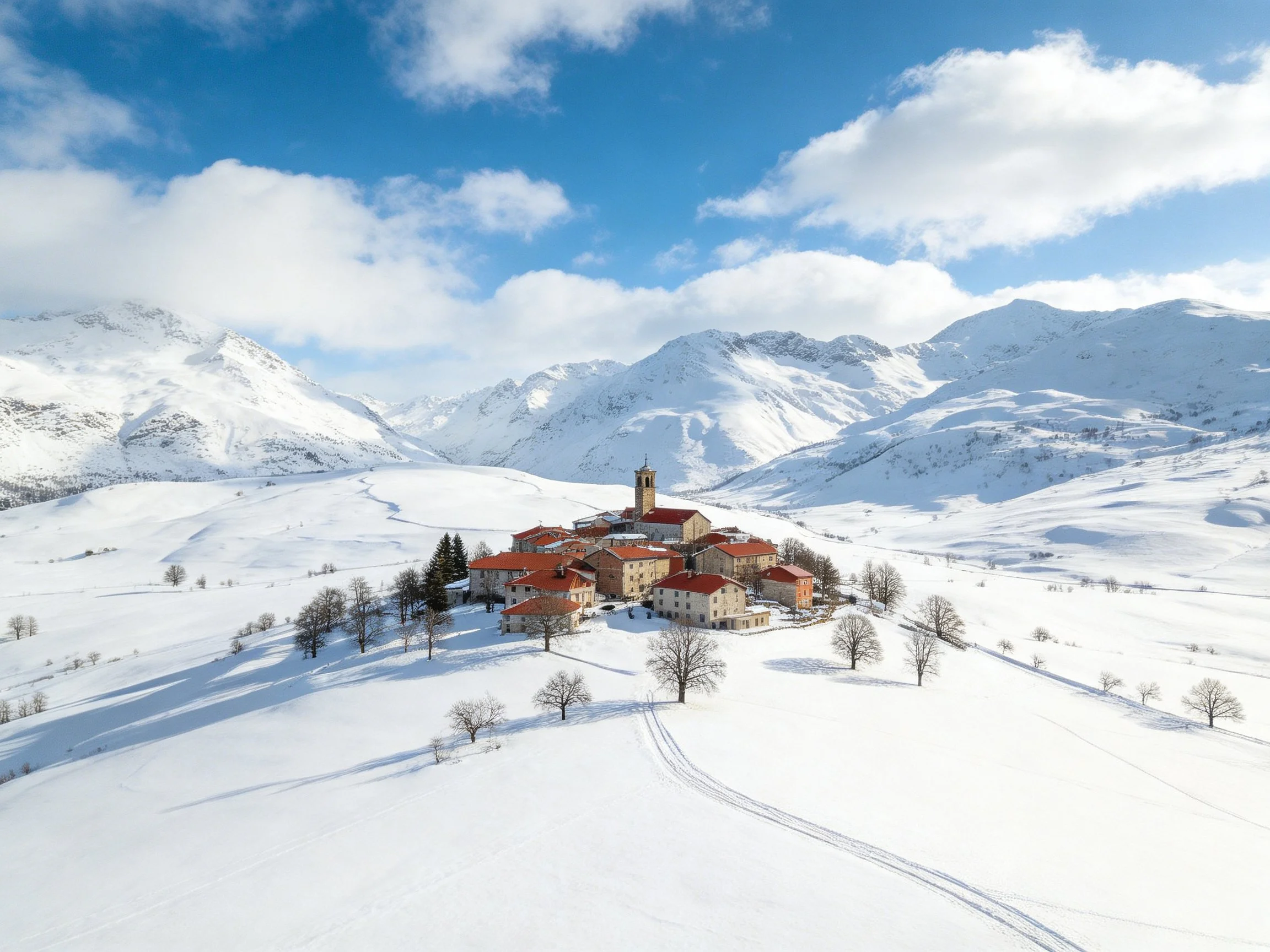 Small village with red-roofed buildings in snowy mountain valley