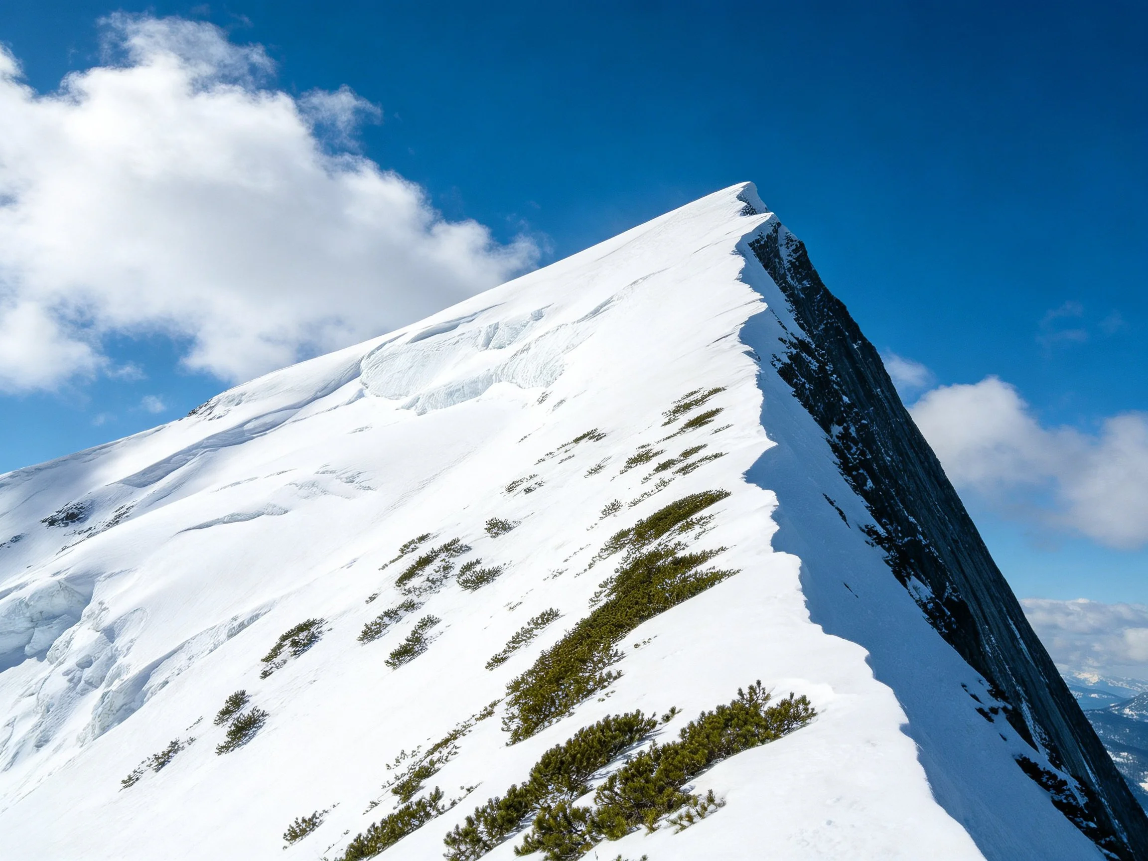 Snow-Capped Mountain Peak with Green Vegetation Under Clear Blue Sky