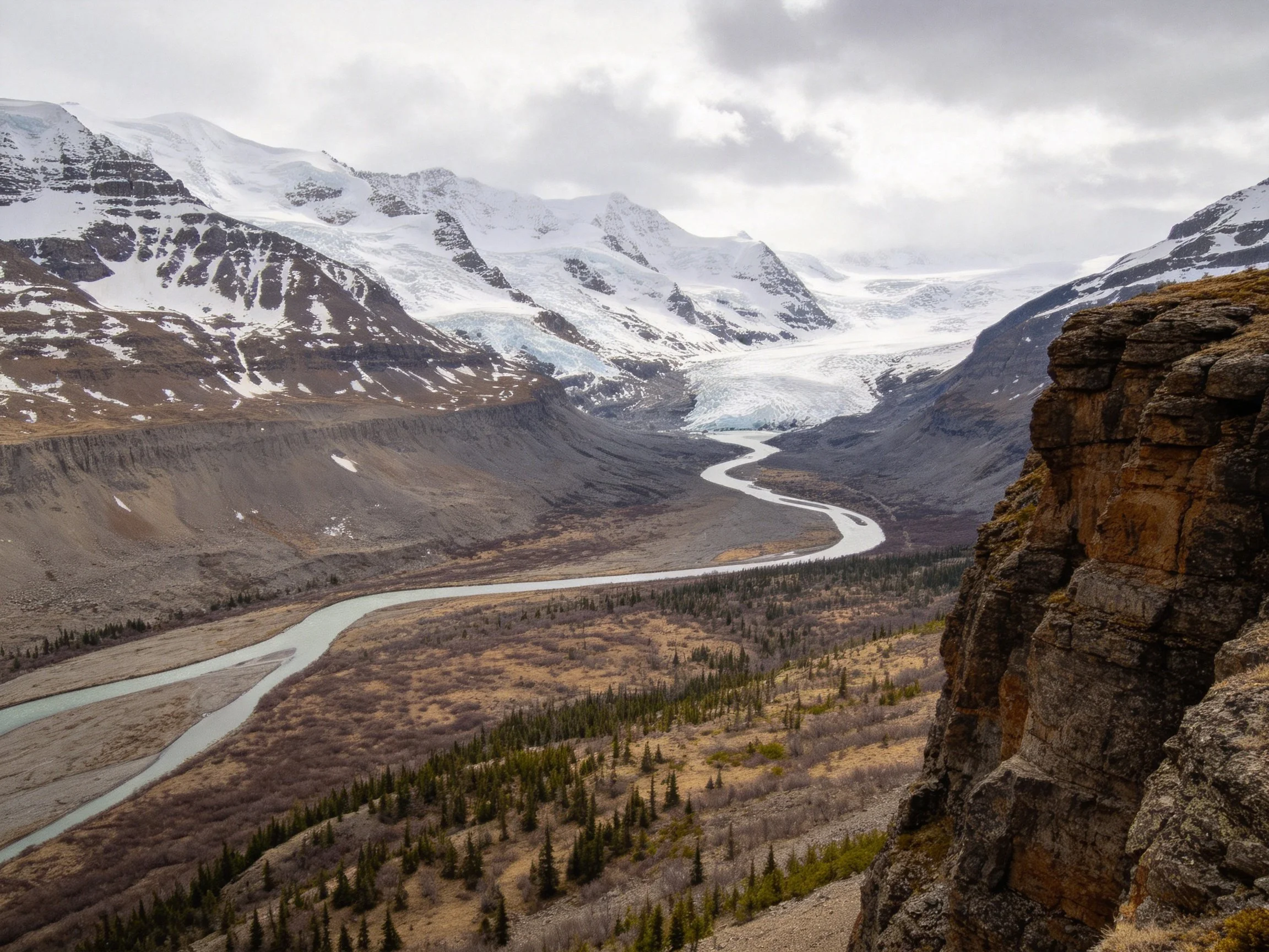 Snow-Capped Peaks Overlook Winding River Through Rocky Valley