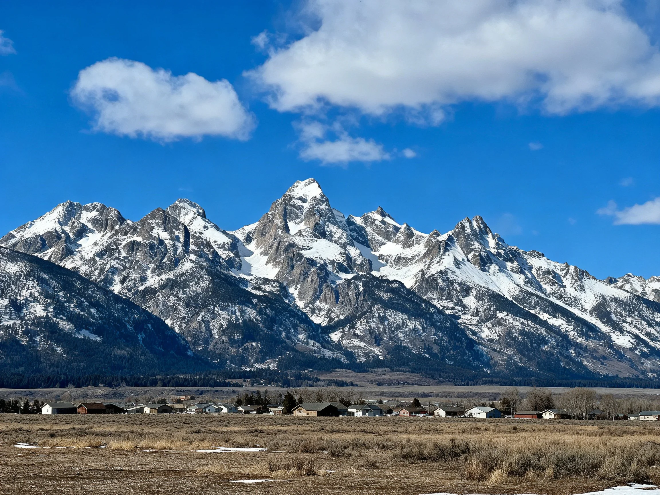 Snow-Capped Peaks Overlook a Scenic Town Under Blue Sky