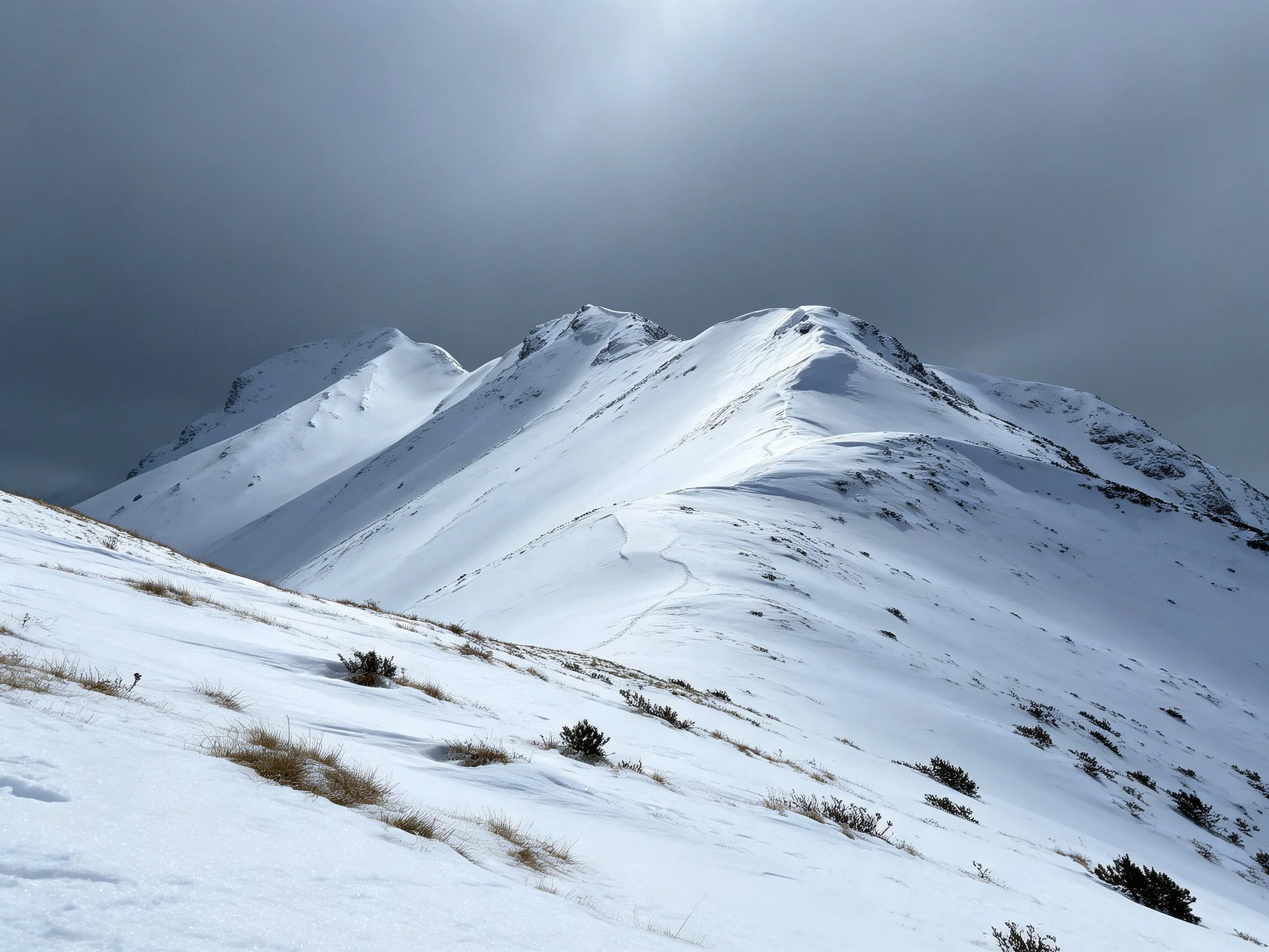 Snow-Covered Mountain Peaks Under Dark Overcast Skies