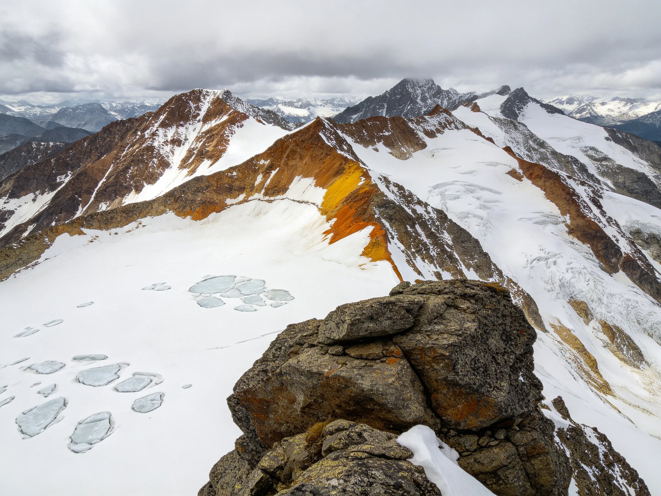 Snow-Covered Mountain Peaks with Rocky Foreground and Earth-Tone Formations