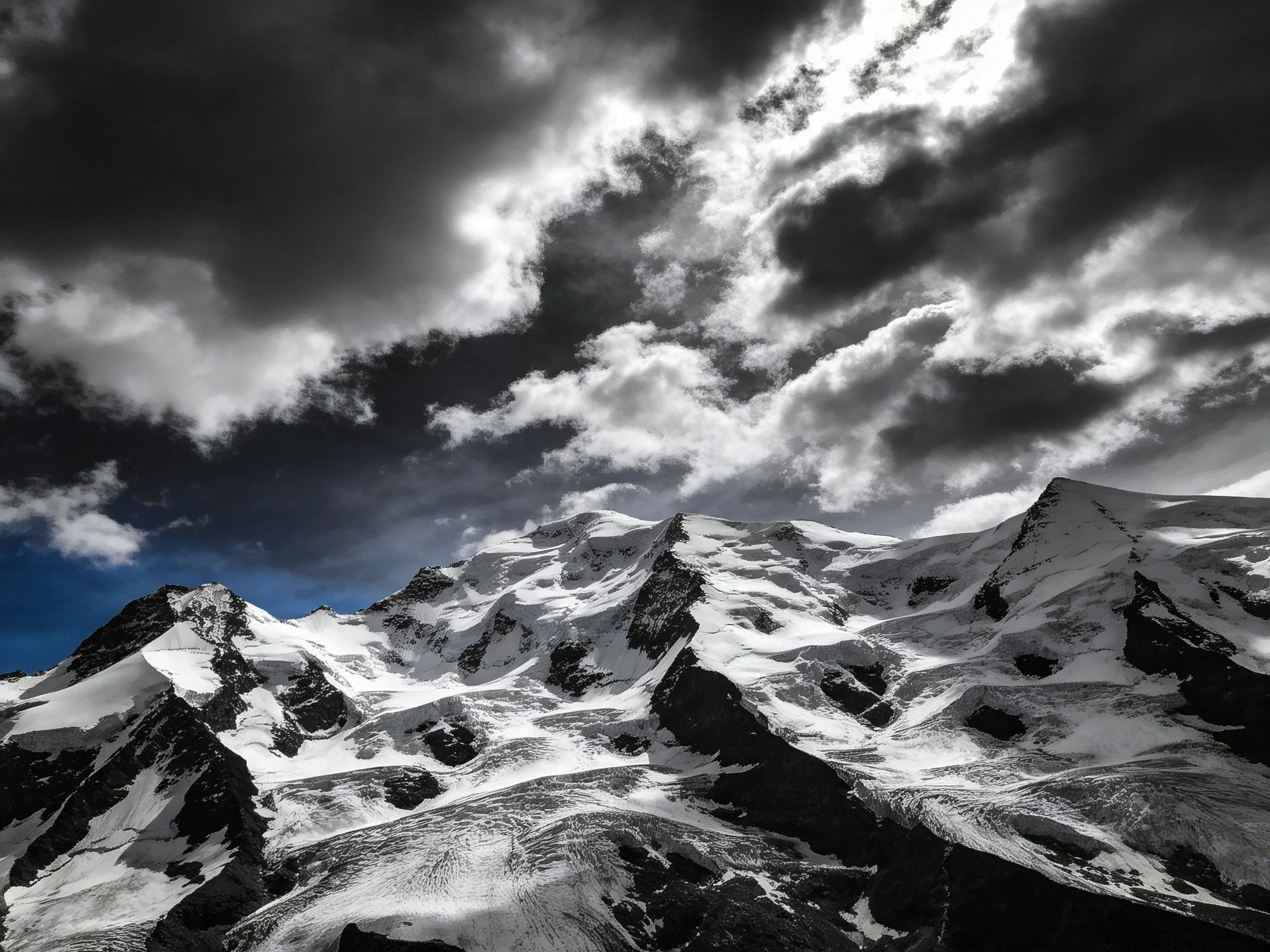 Snow-Covered Peaks Under Dark, Dramatic Cloudy Skies