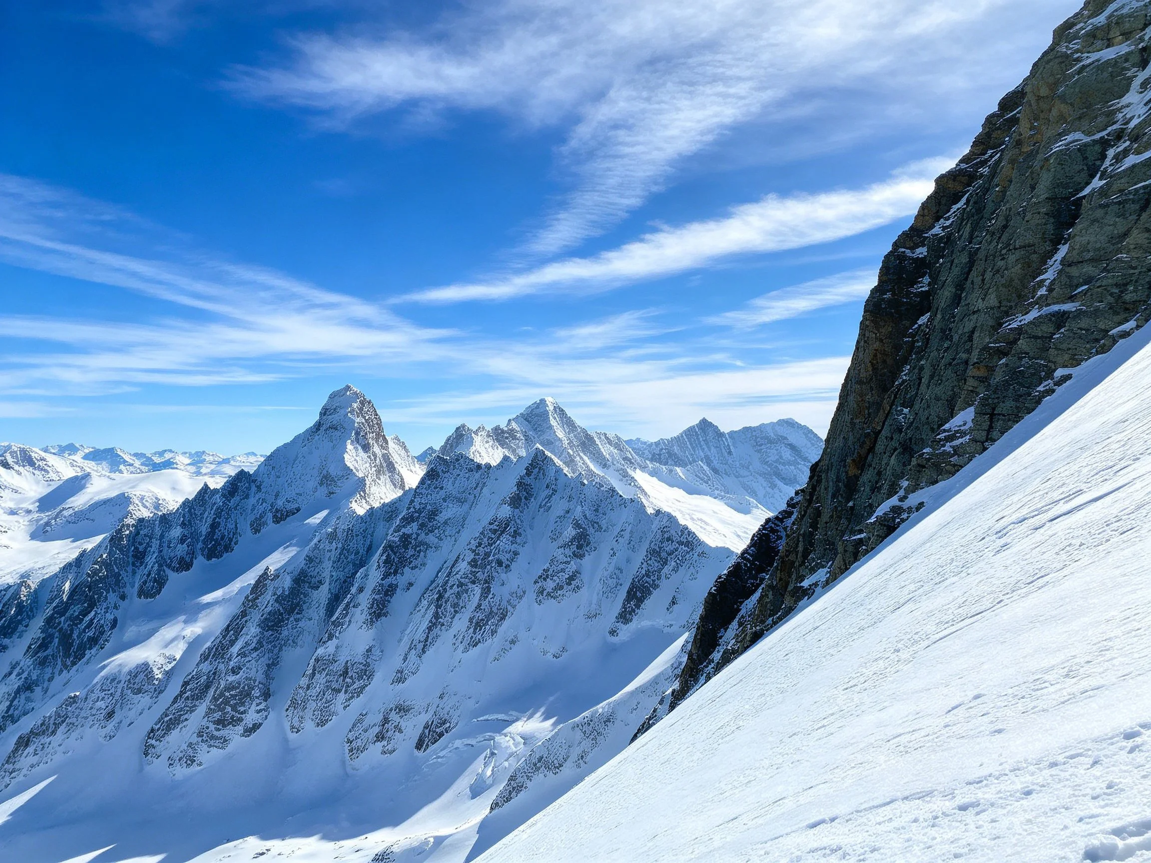 Snow - capped Peaks and Rocky Slopes Under Clear Blue Skies