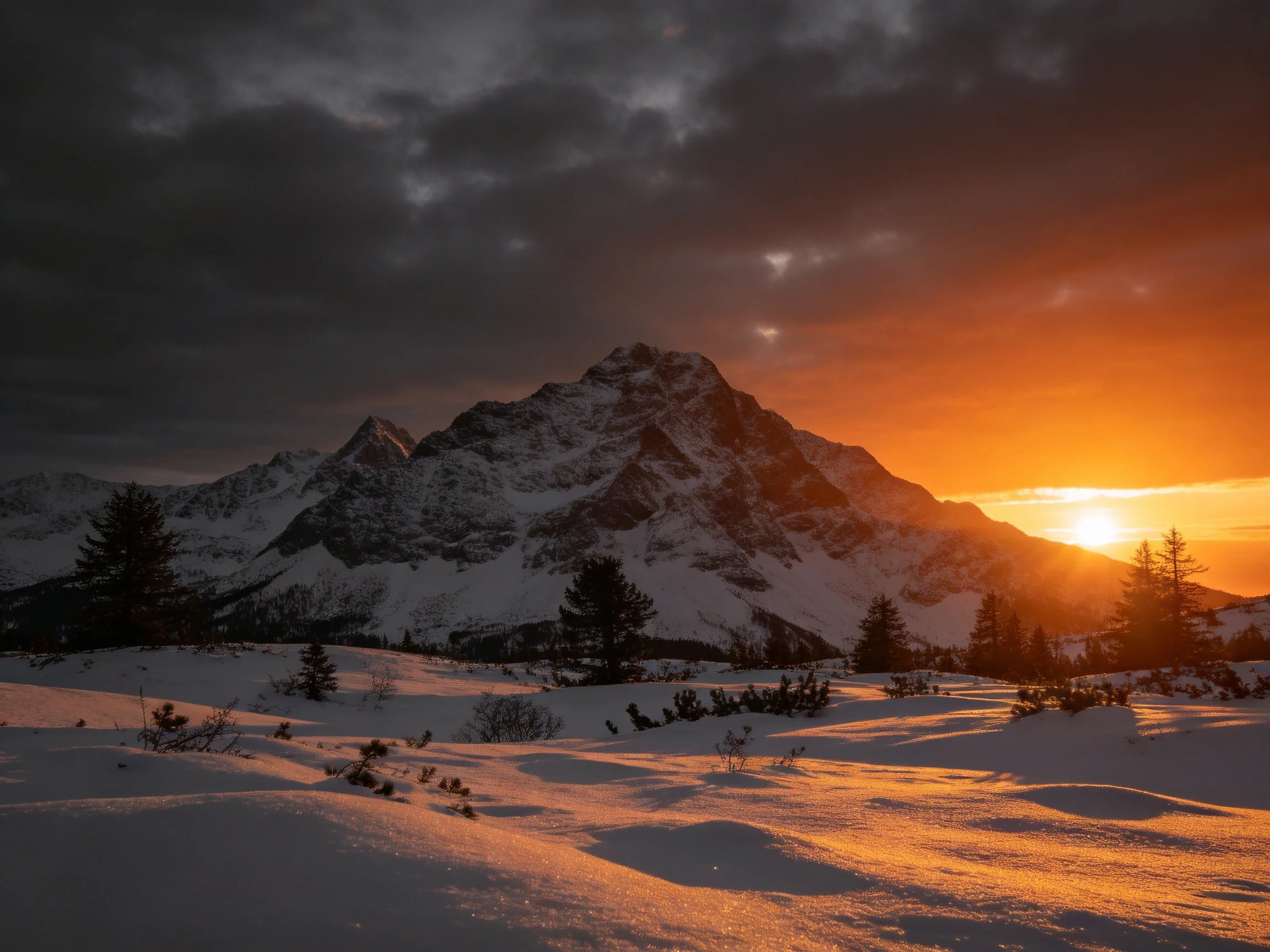 Snow - capped mountain peak at sunset with dramatic cloudy sky