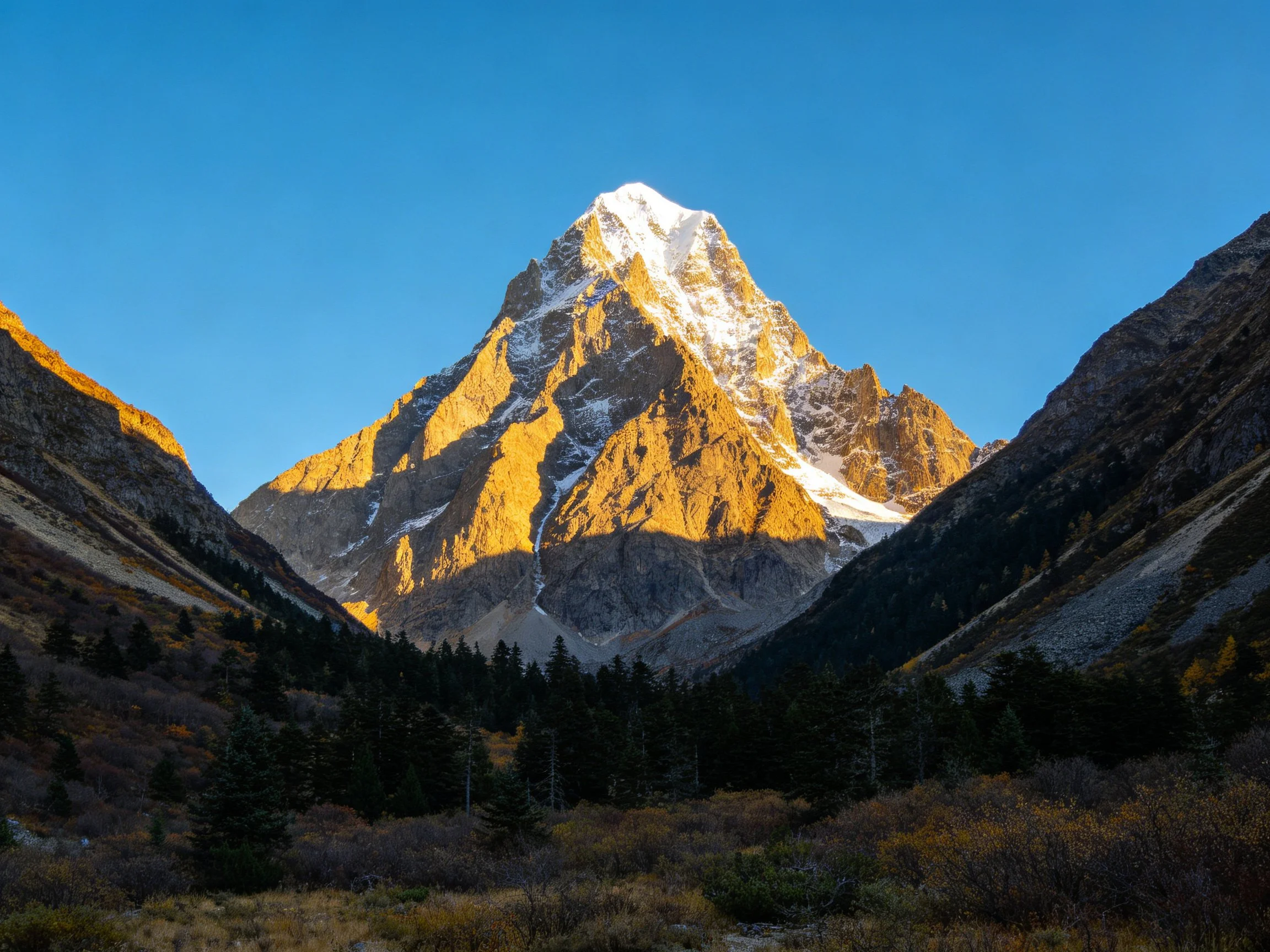 Snow-capped mountain peak glowing in golden sunlight
