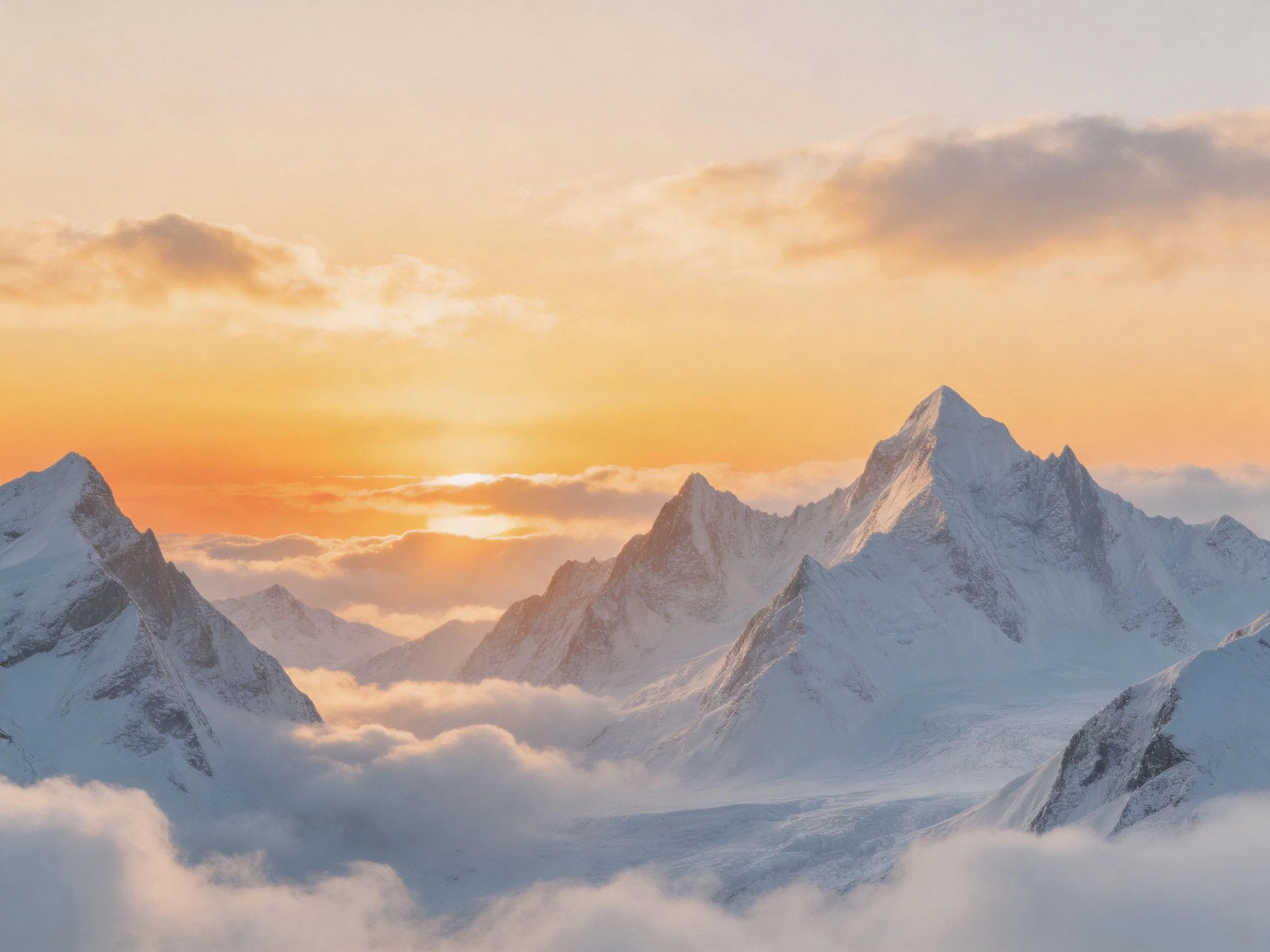 Snow-capped mountain peaks beneath a warm sunset sky