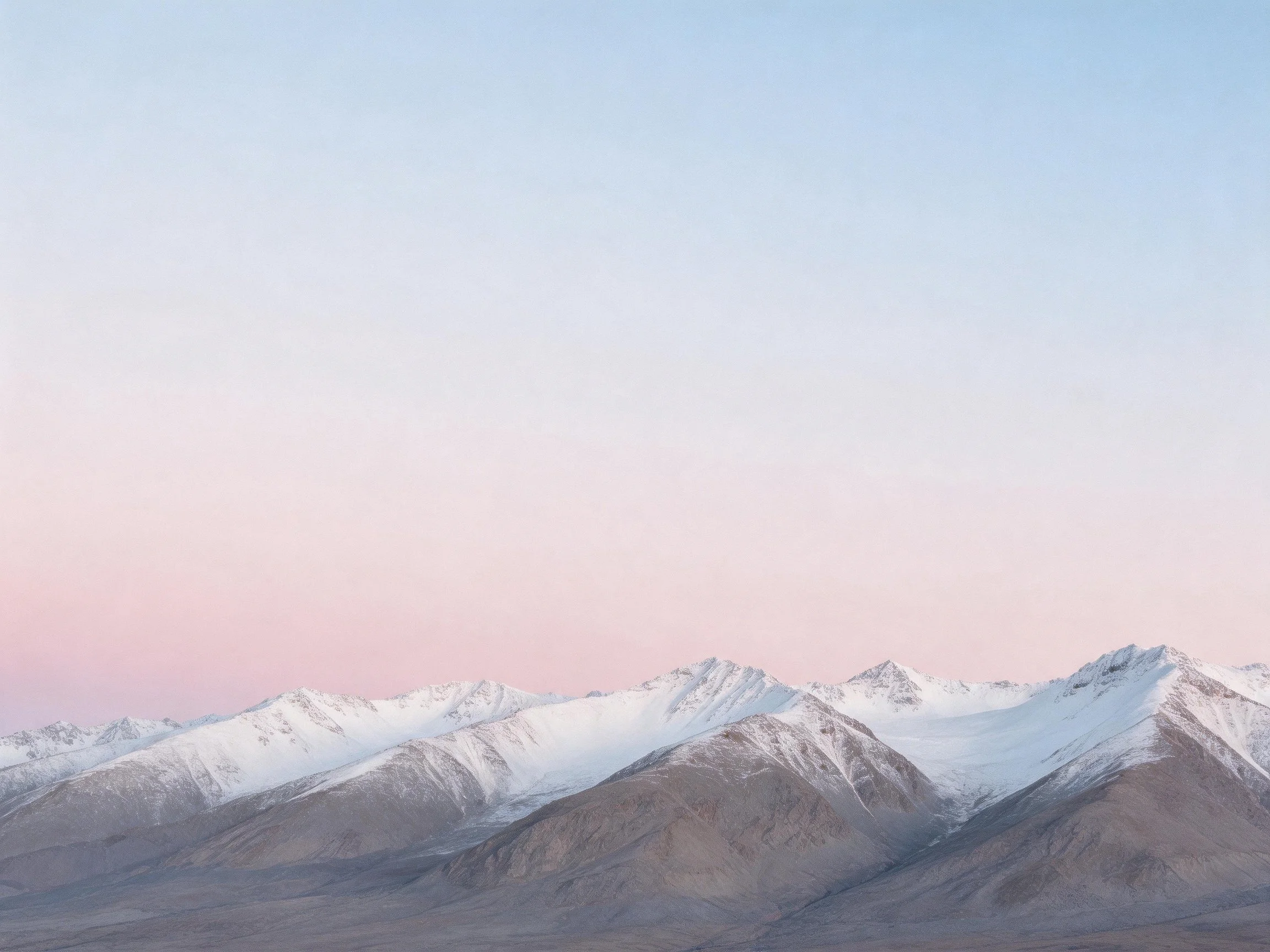 Snow-capped mountain peaks beneath pastel sky