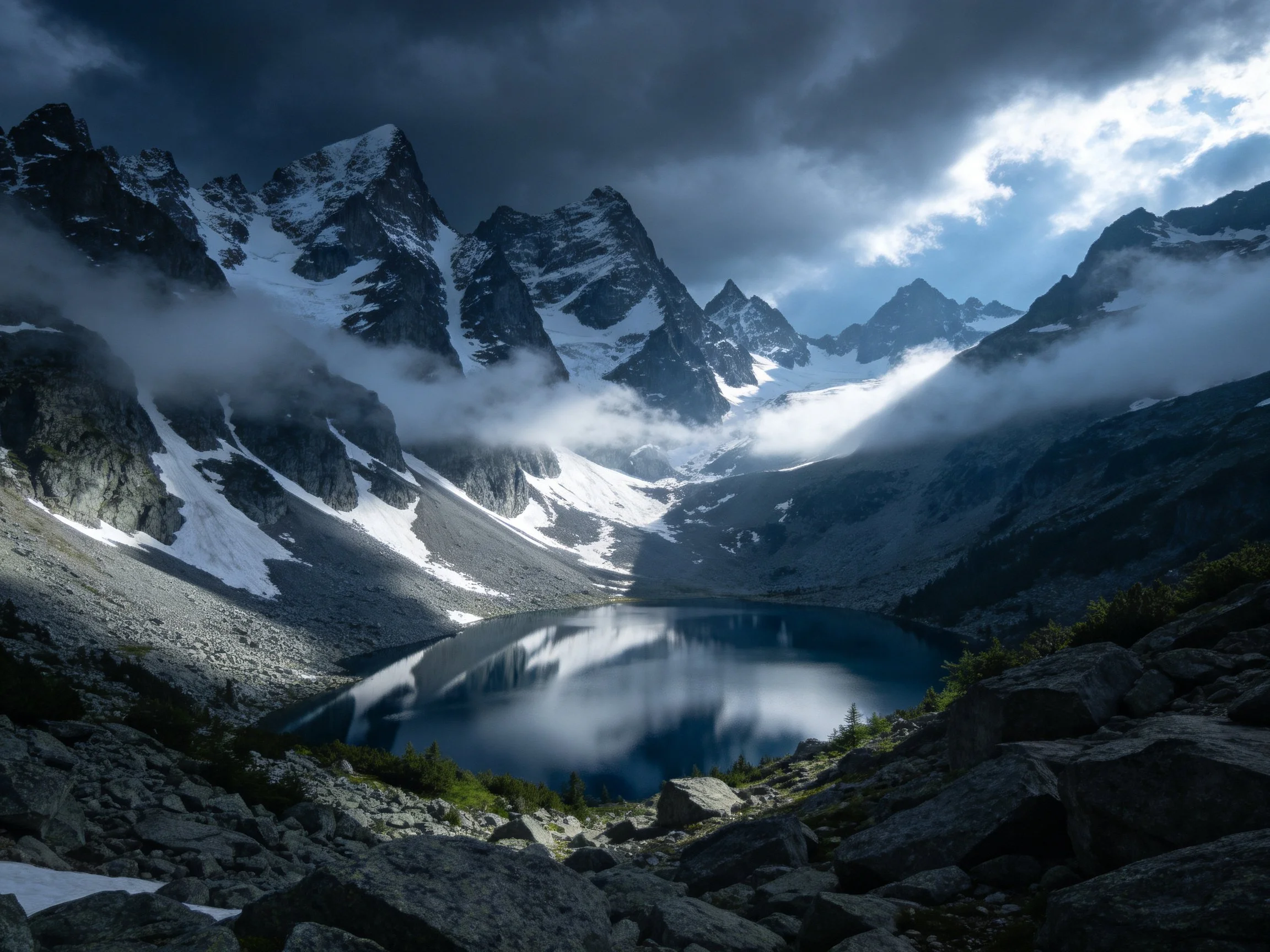 Snow-capped mountain peaks encircle a reflective alpine lake under moody skies