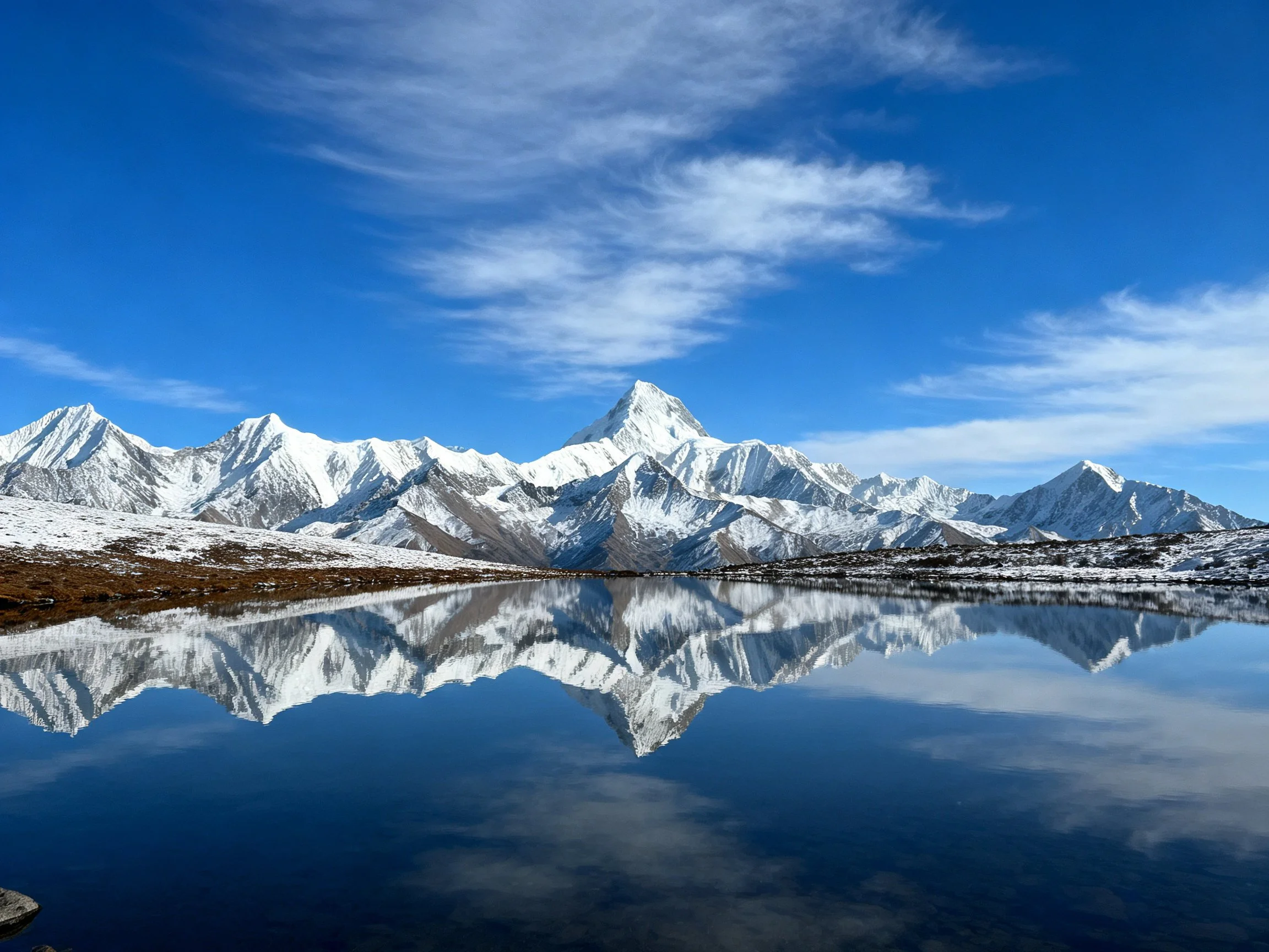 Snow-capped mountain peaks reflected in crystal-clear alpine lake