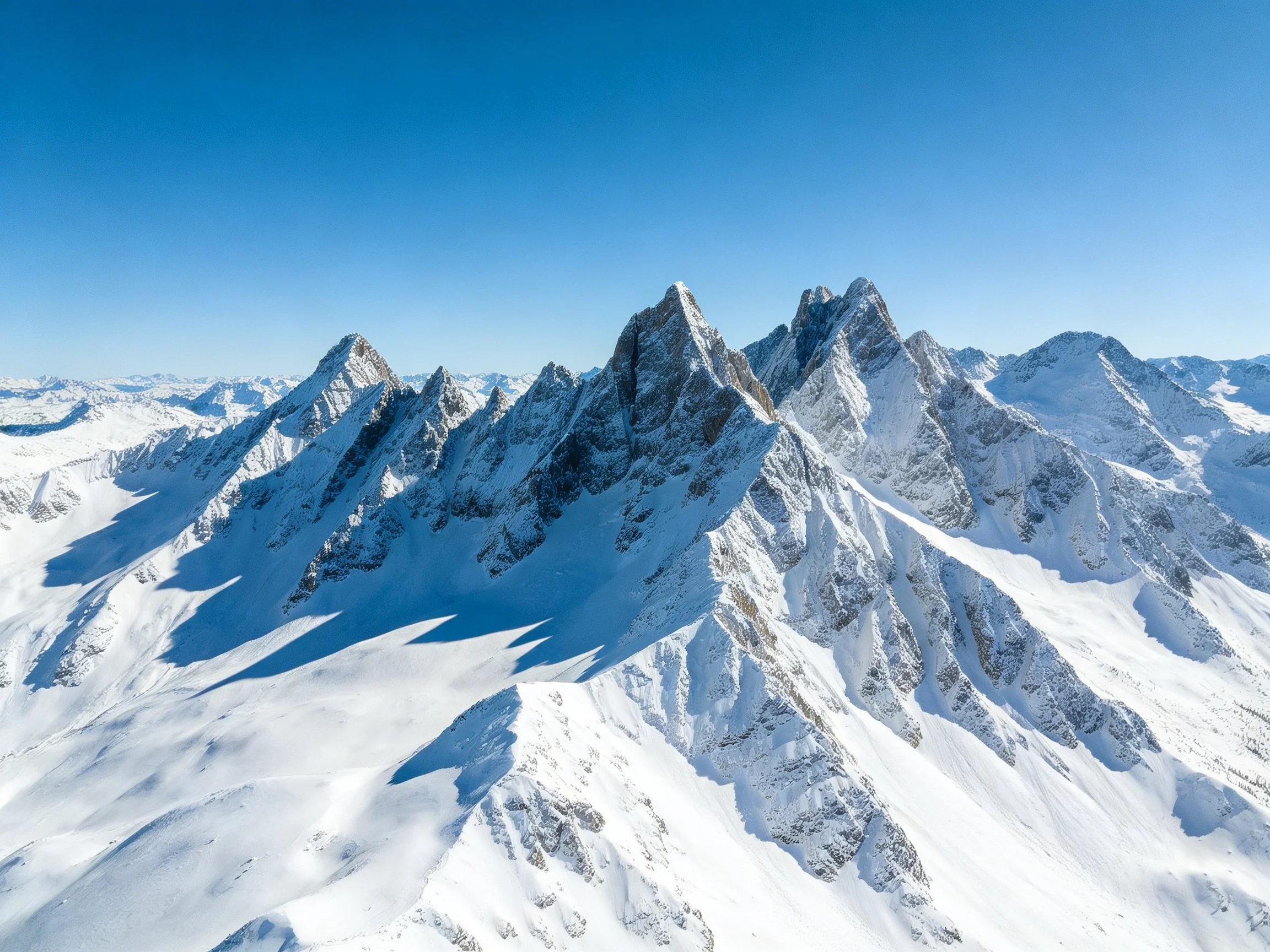 Snow-capped mountain peaks stretching into clear blue sky