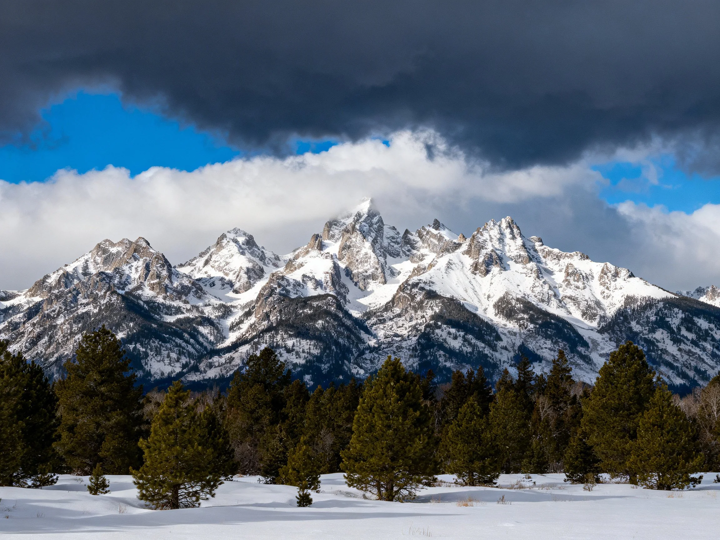Snow-capped mountain peaks under dramatic cloud-filled sky