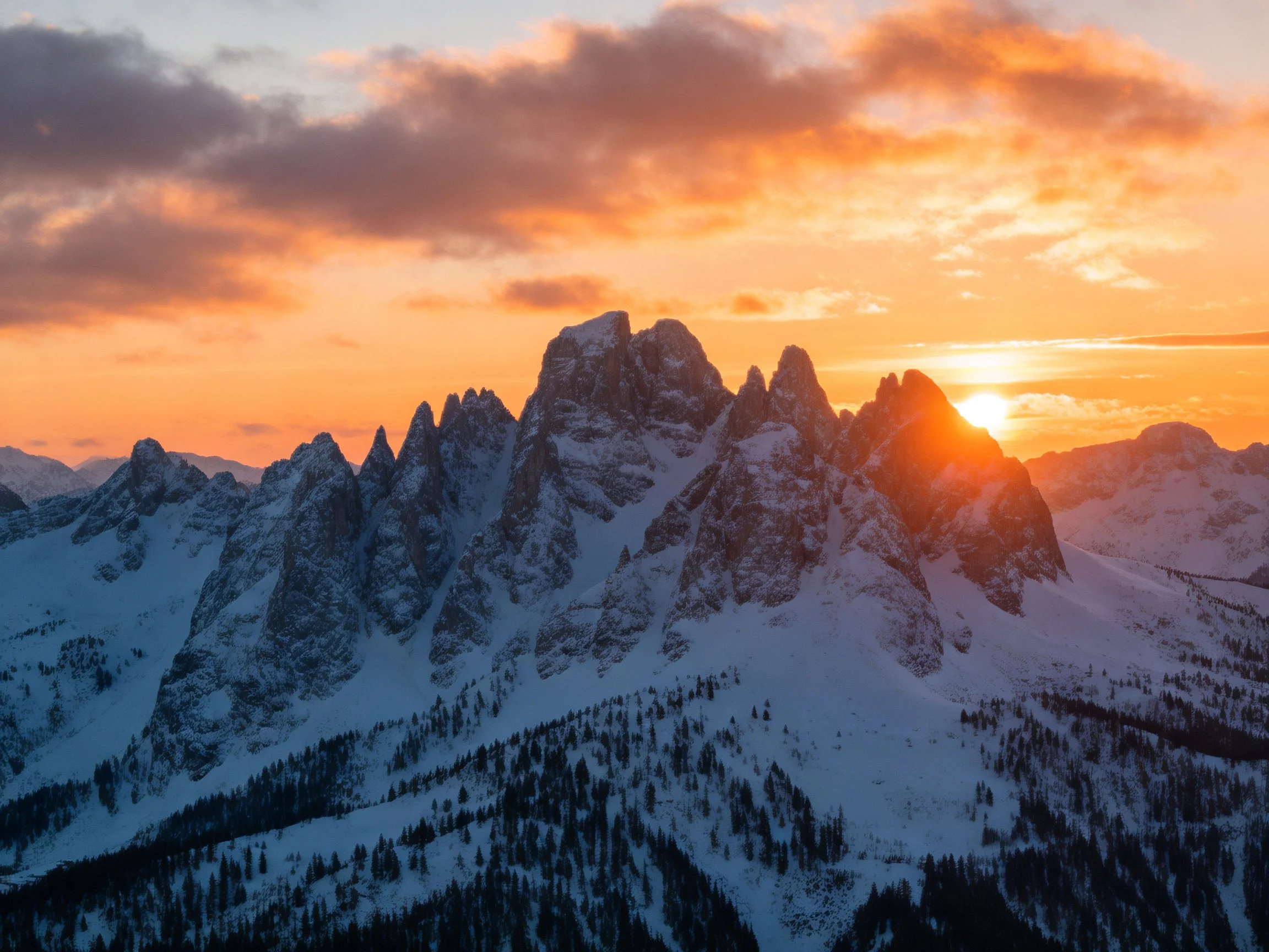 Snow-capped mountain peaks under vibrant sunset skies