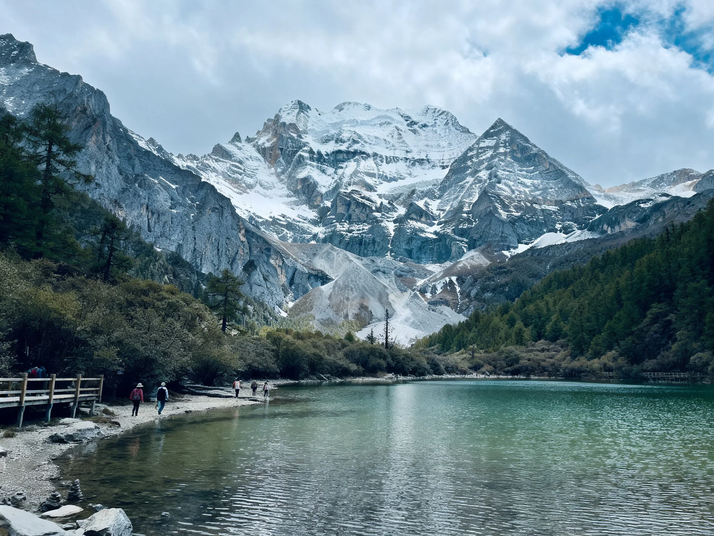 Snow-capped mountains overlook a turquoise glacial lake with wooden pathways