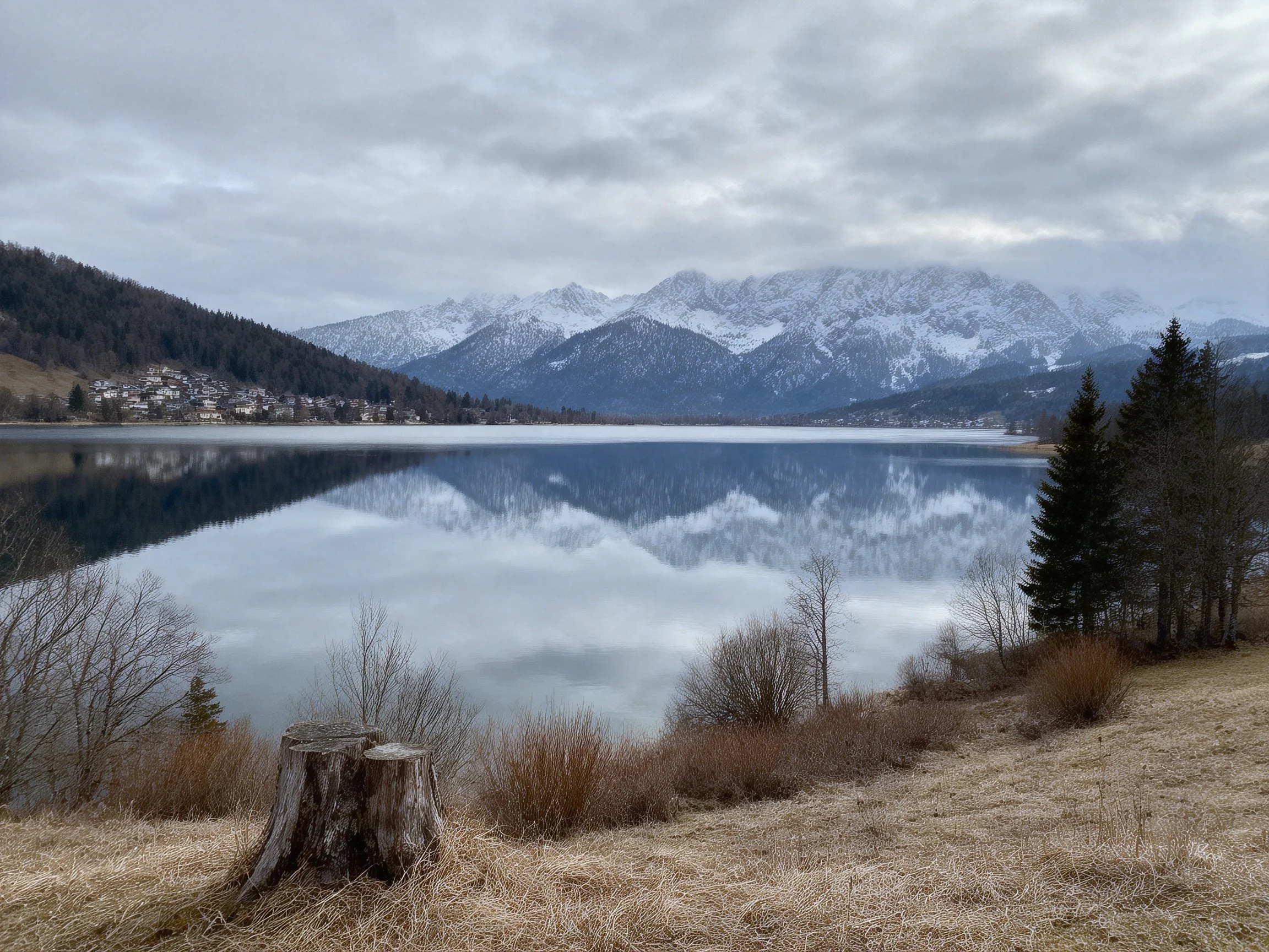 Snow-capped mountains reflected in tranquil lake near forested shore