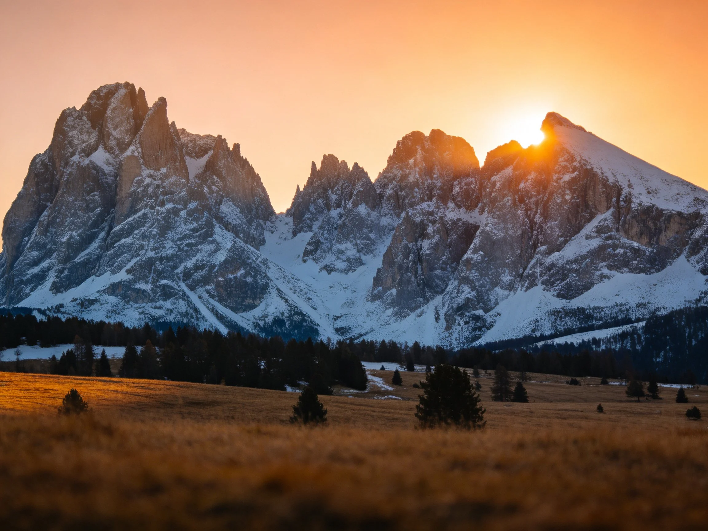 Snow-covered jagged mountains illuminated by warm sunset light
