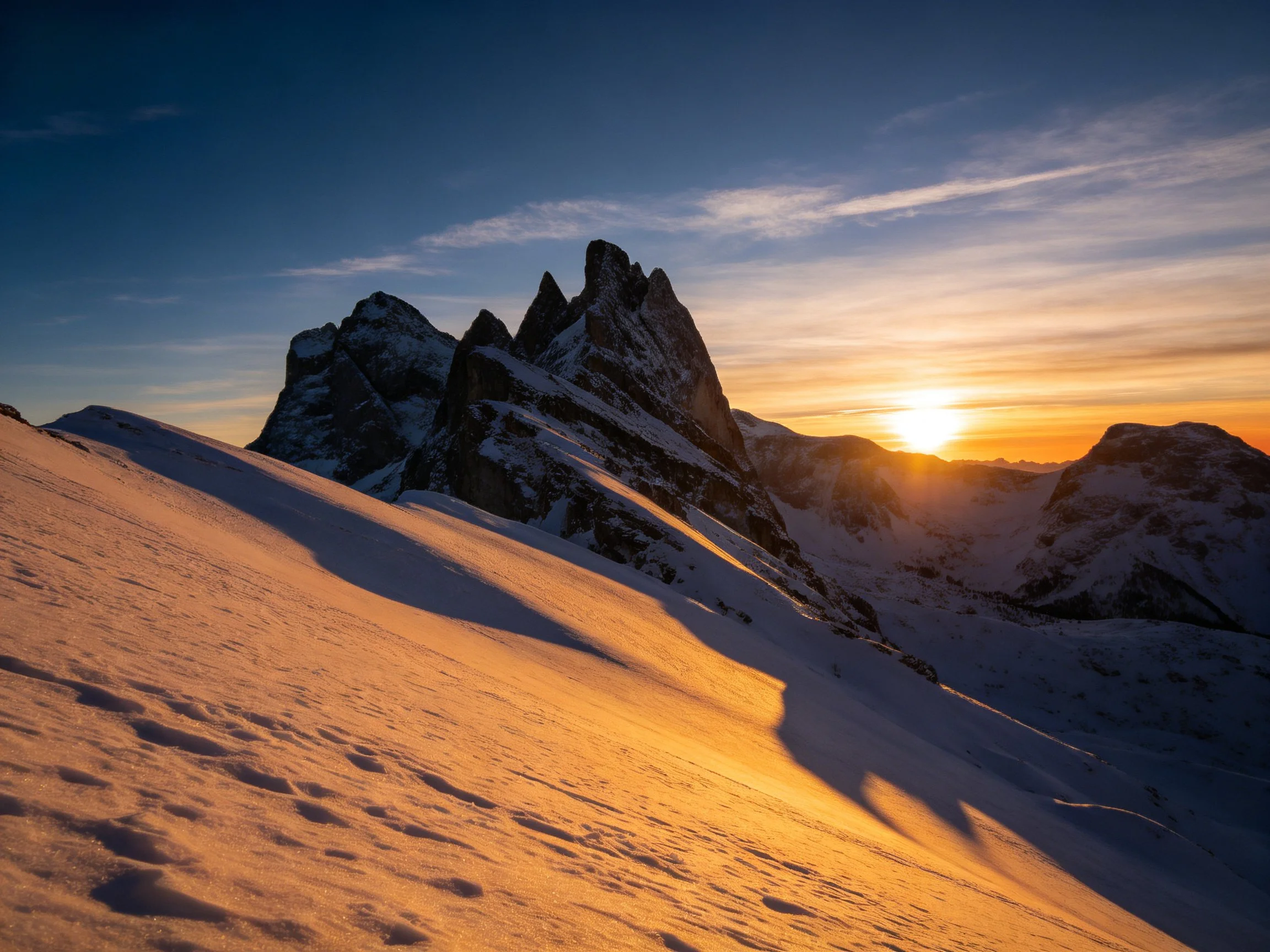 Snow - covered mountain peaks illuminated by golden sunset