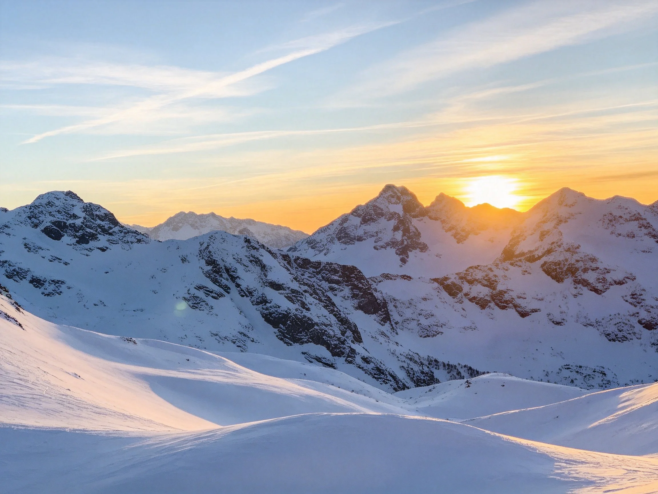Snow-covered mountain peaks illuminated by golden sunset light