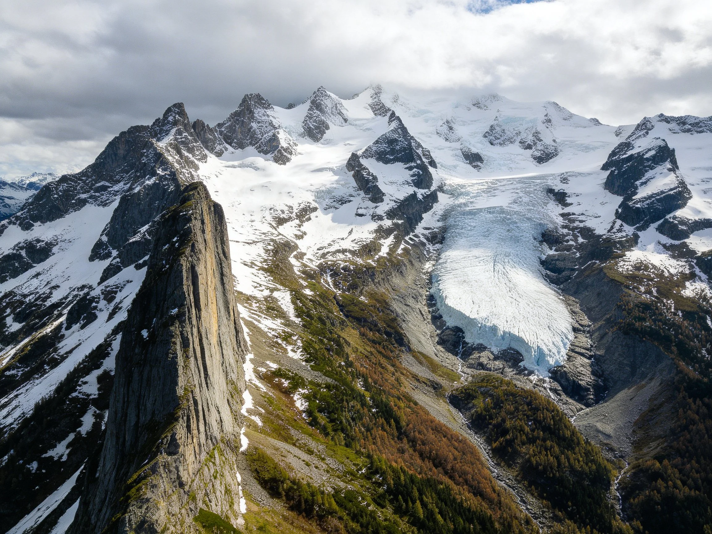 Snow-covered mountain peaks with dramatic rock formations and forested valleys