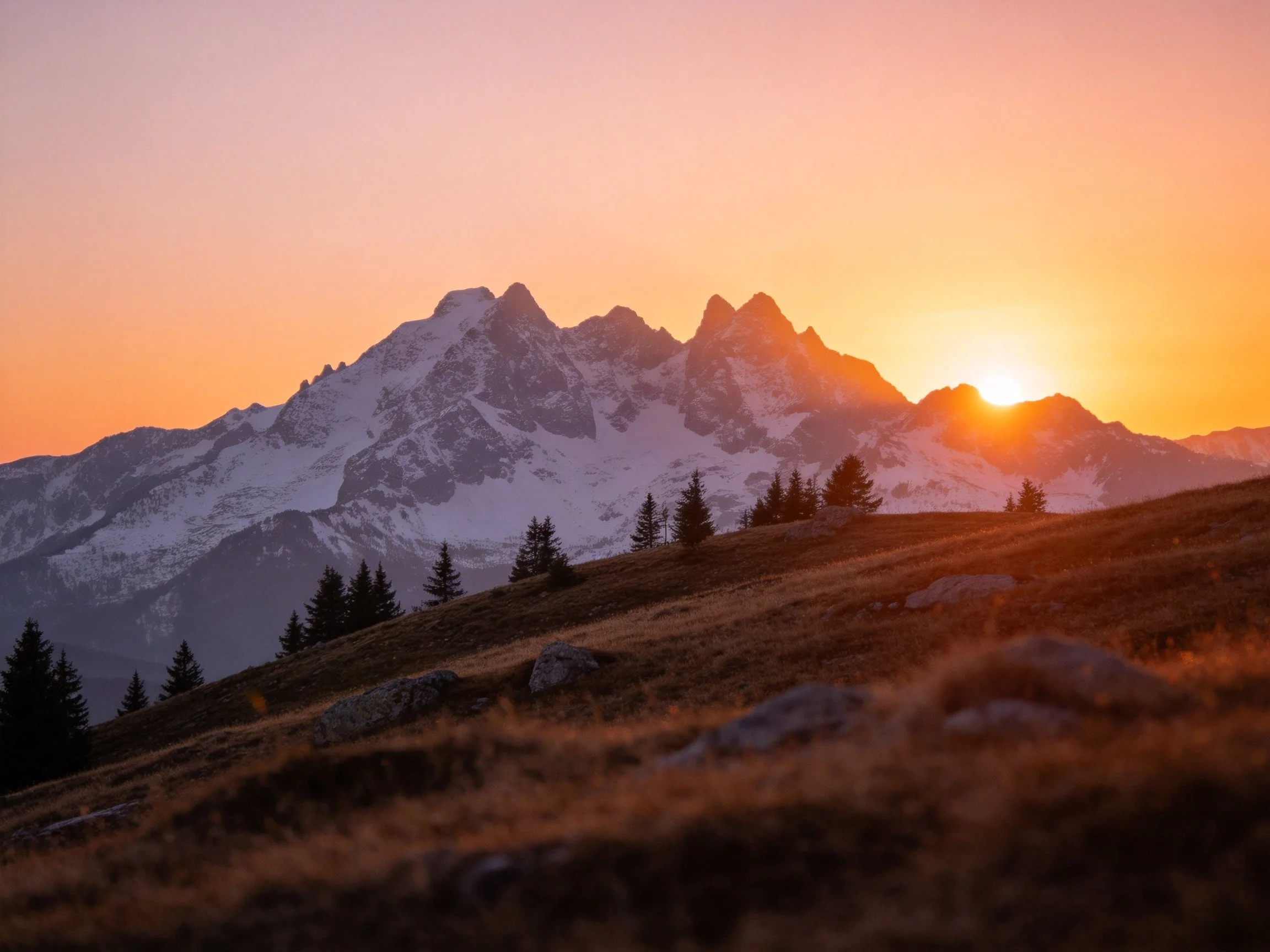 Snow-dusted mountain peaks illuminated by warm sunset light