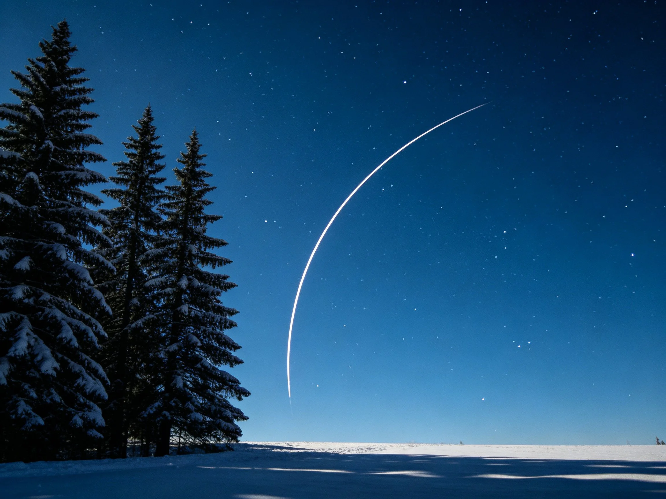 Snowy landscape with pine trees and a bright celestial arc