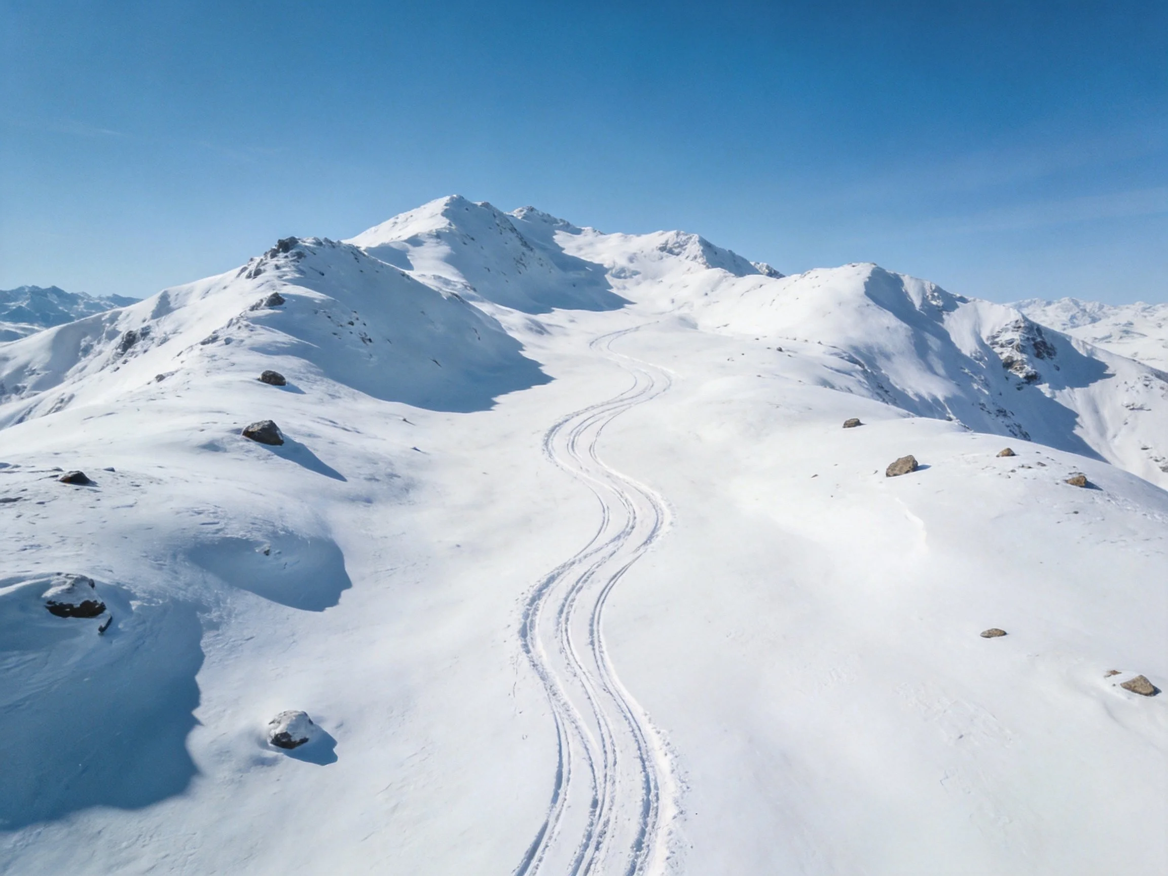 Snowy mountain slopes with winding ski tracks and rocky terrain