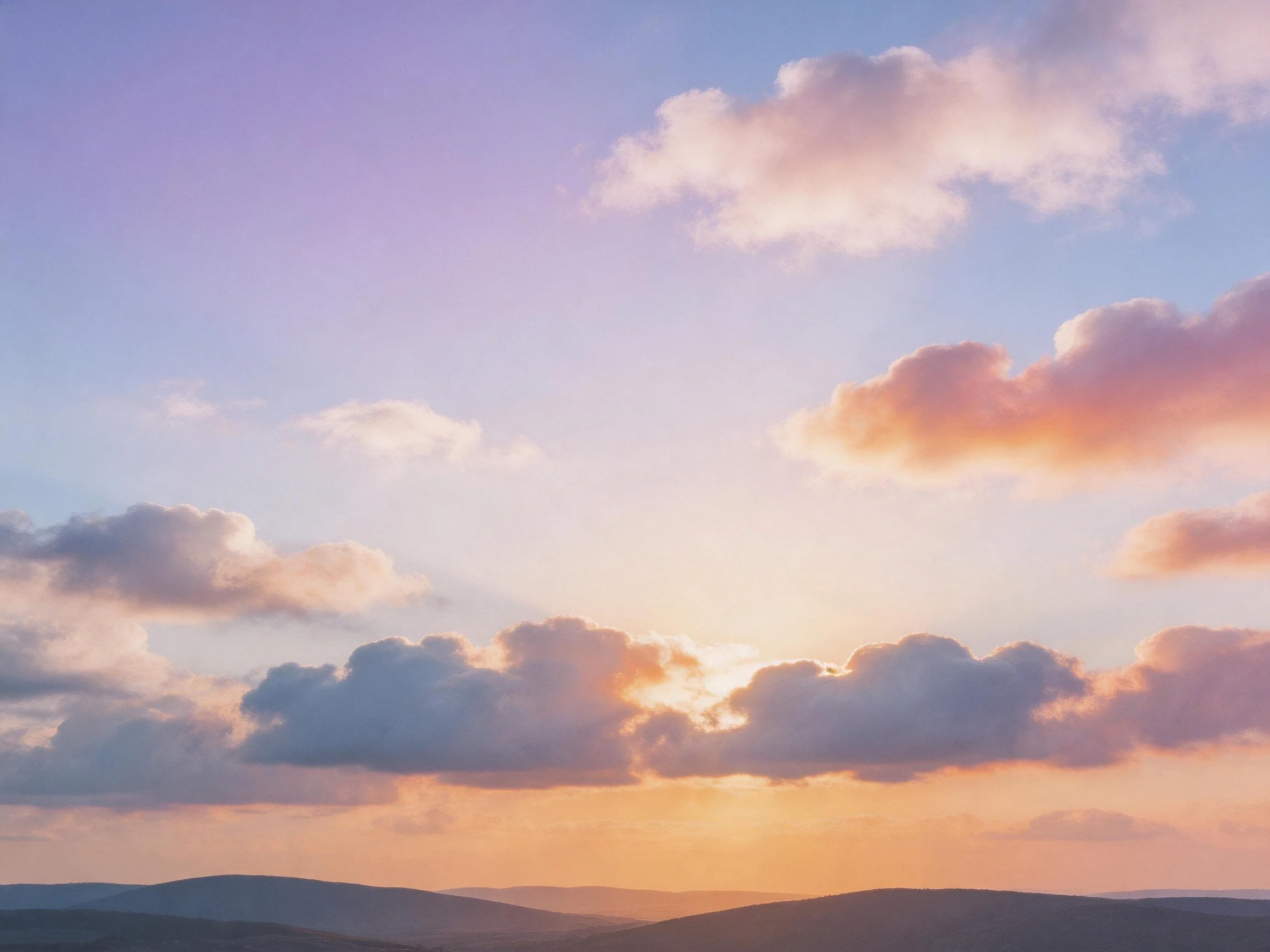 Soft pastel clouds in a gradient sky above distant hills