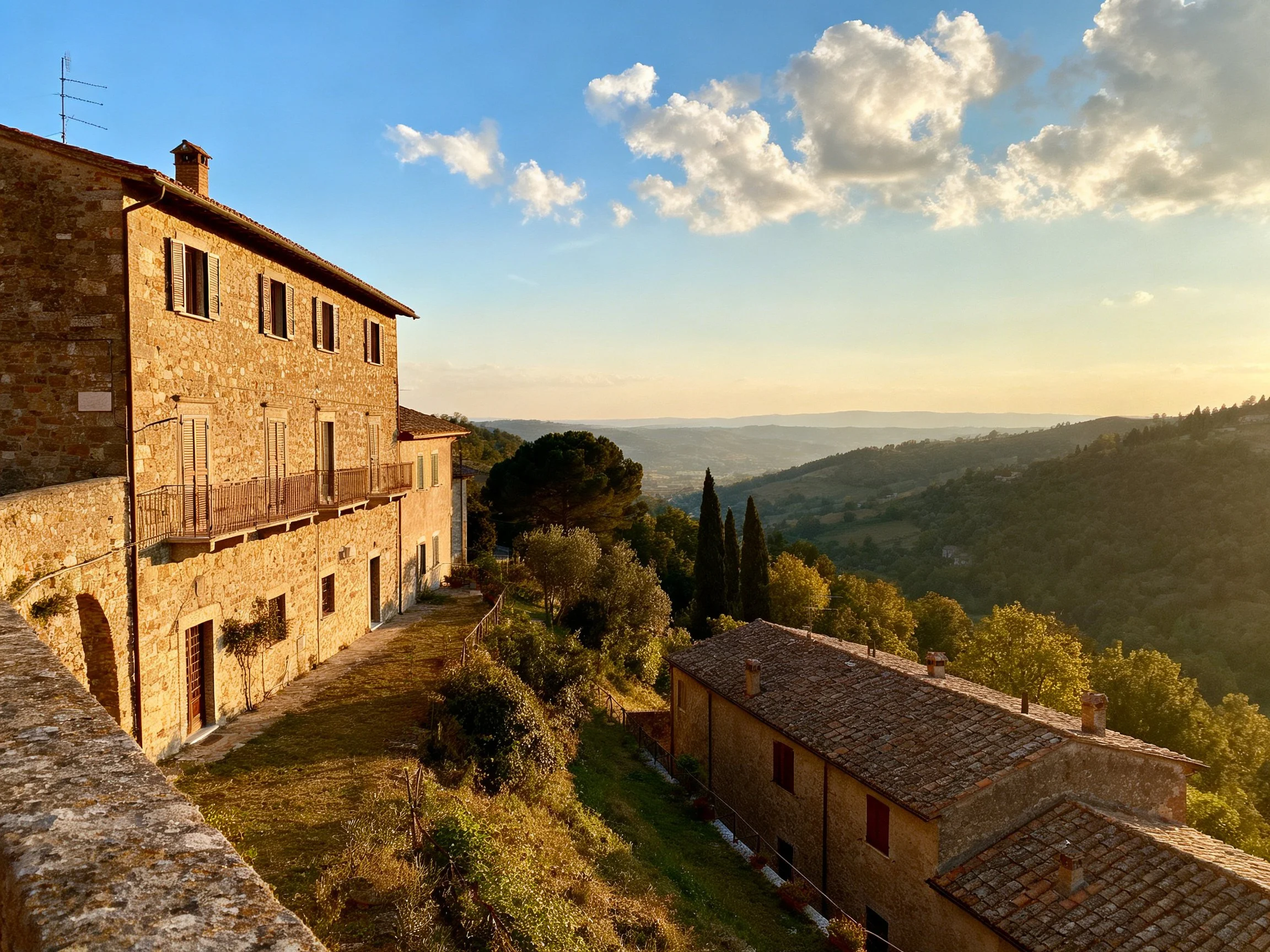 Stone houses on a hillside overlook rolling green hills under blue sky