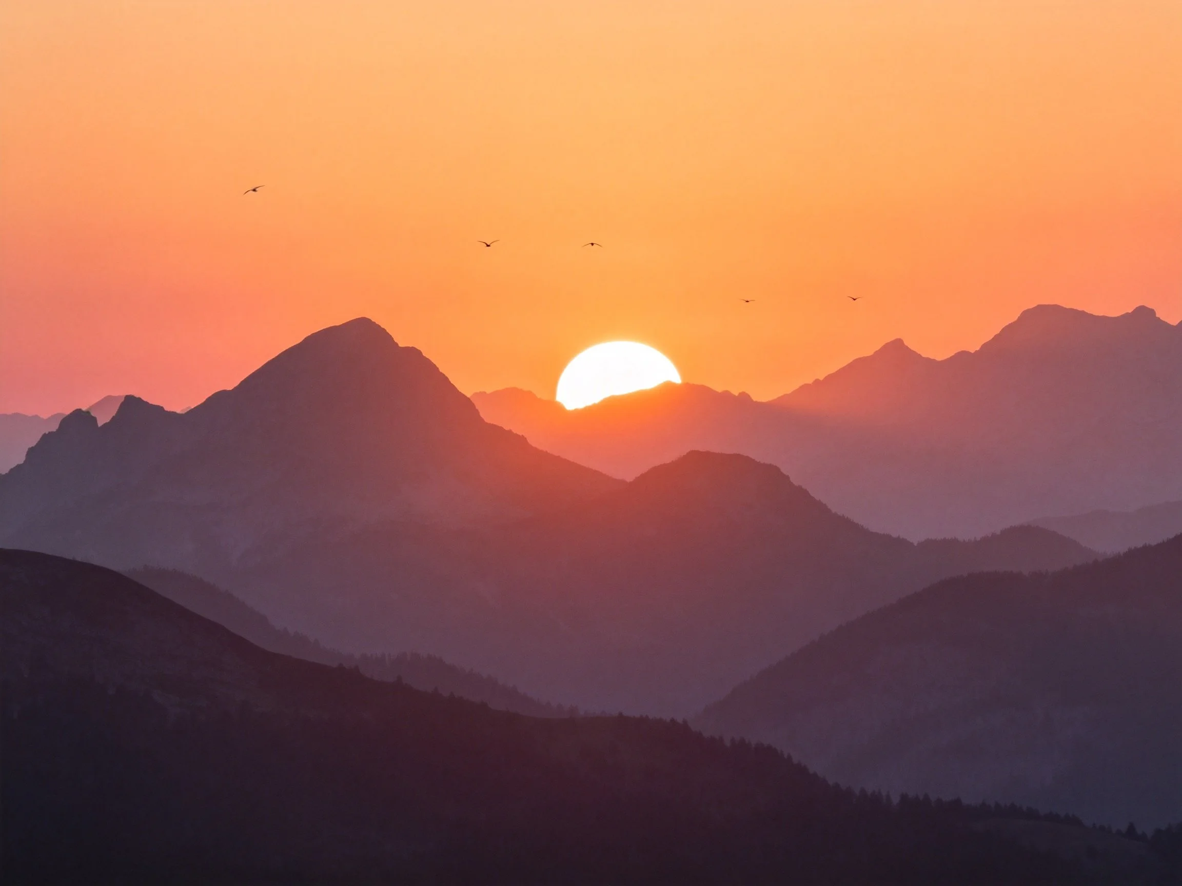 Sunset Over Layered Mountain Ranges with Vibrant Orange Sky