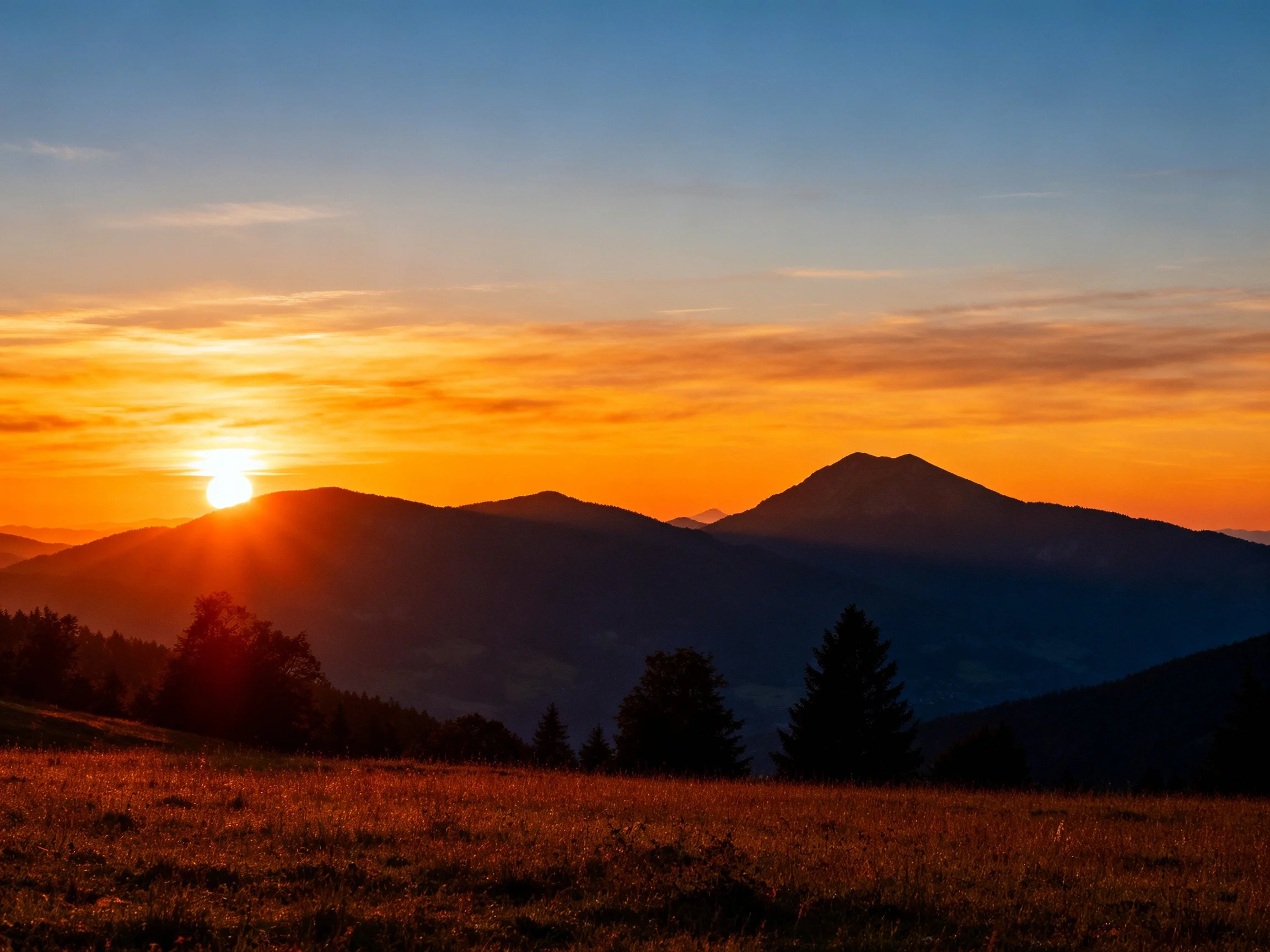 Sunset Over Mountain Peaks With Golden Field