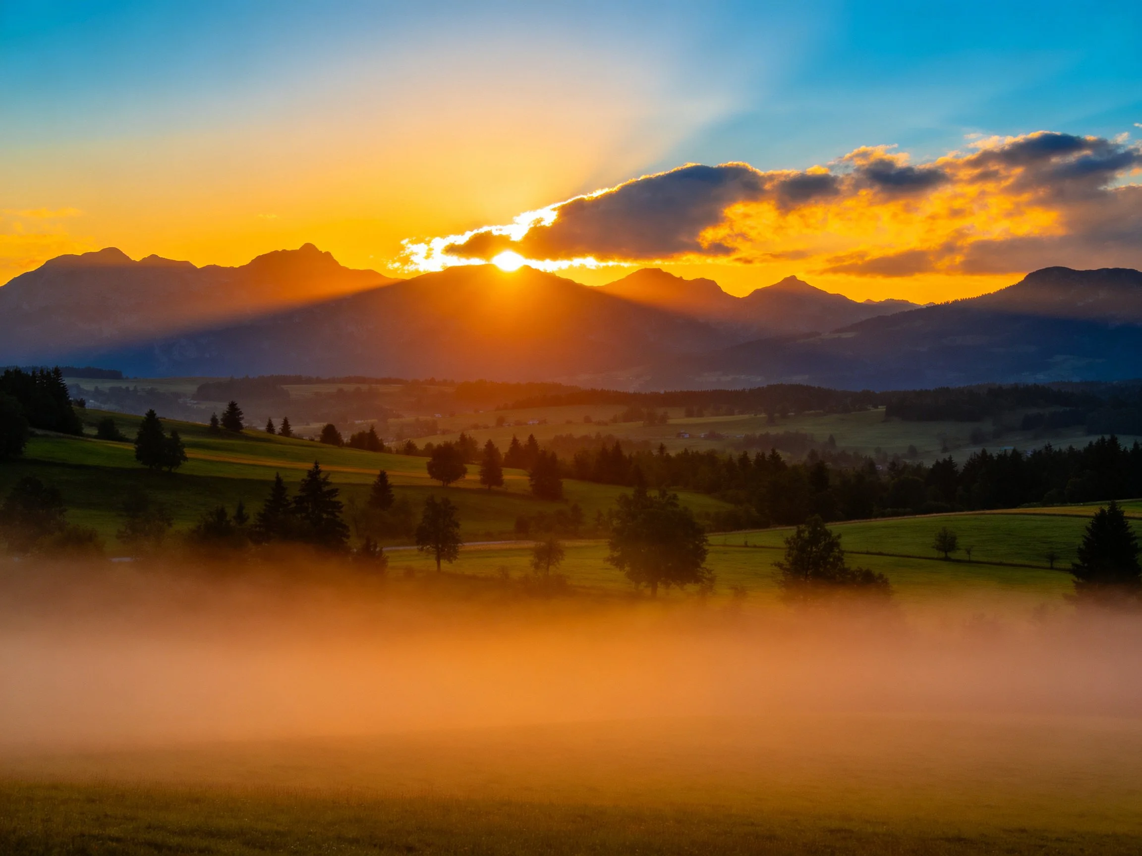Sunset illuminates mountain range with golden foggy valley below
