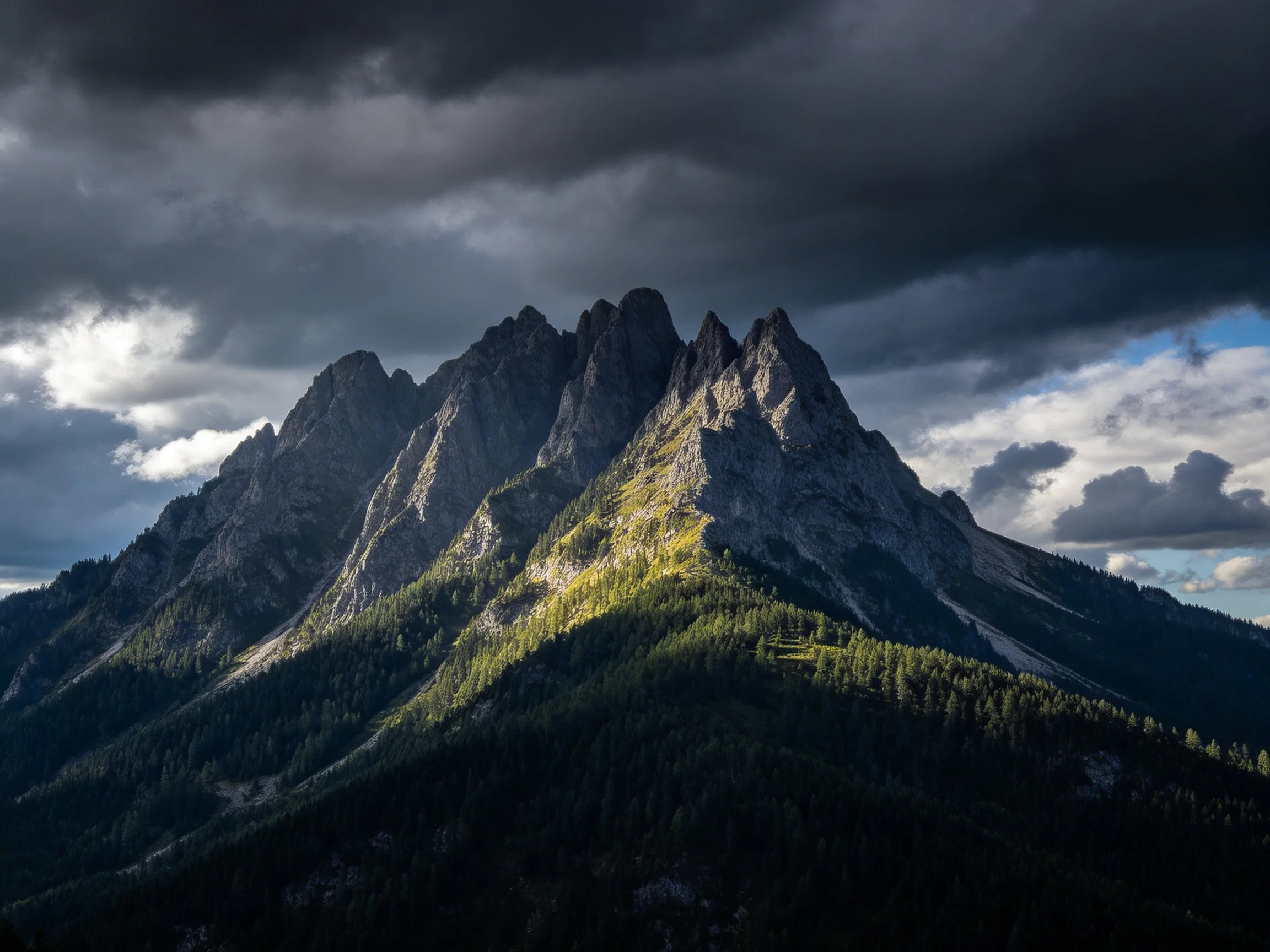 Towering jagged mountain peaks beneath dark storm clouds with forested slopes