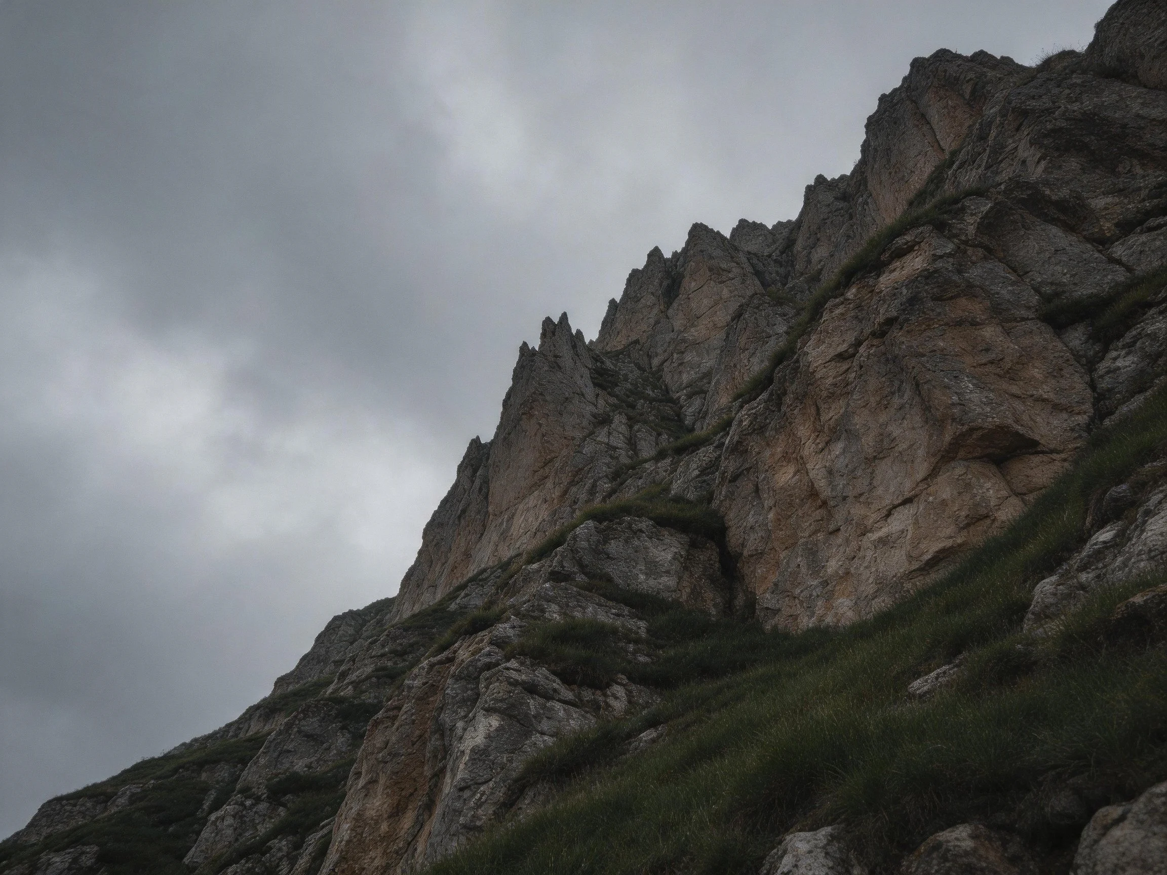 Towering rocky cliffs with lush vegetation against overcast sky