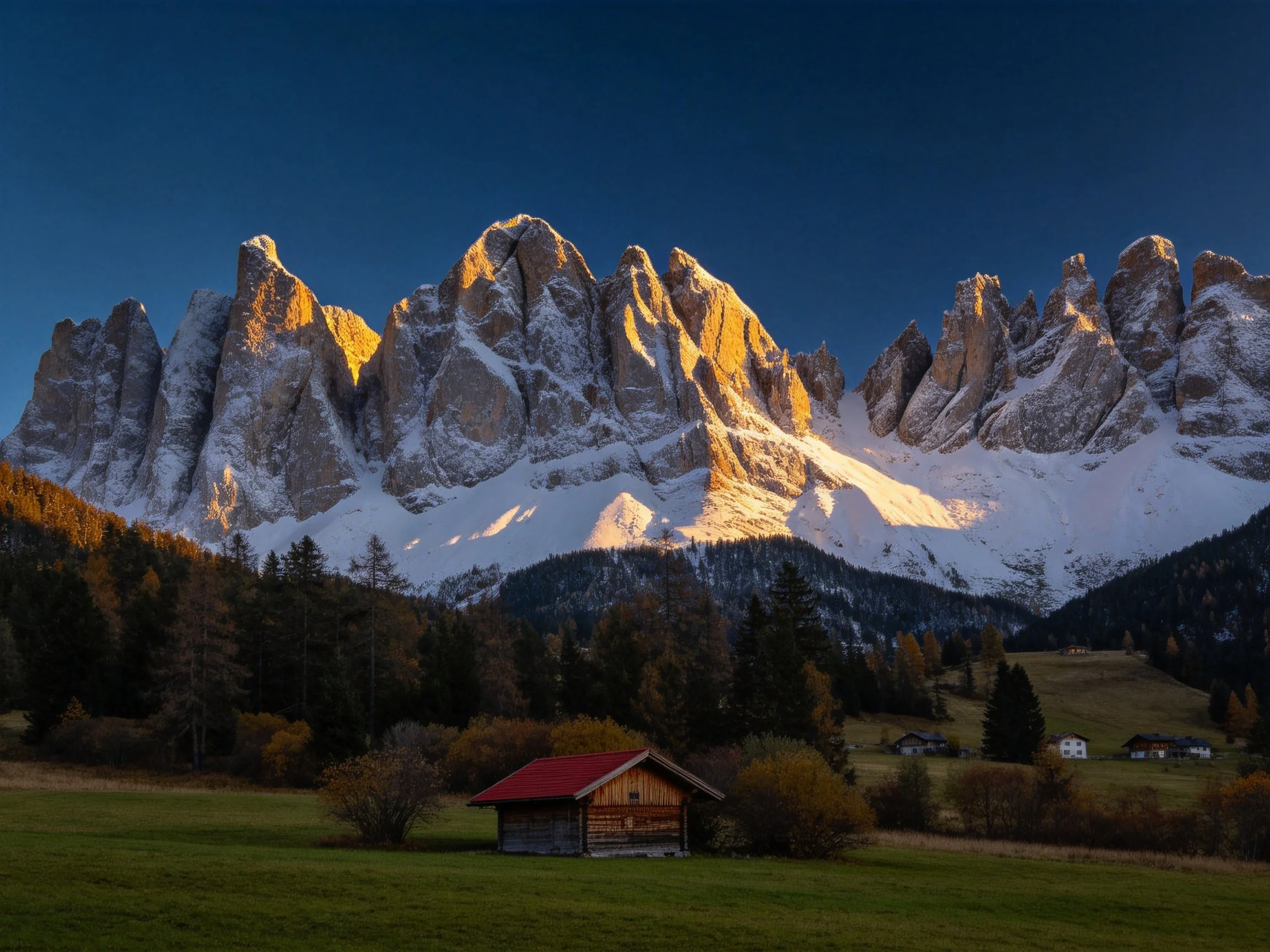 Towering snow - capped peaks glow golden near rustic cabins and green meadows