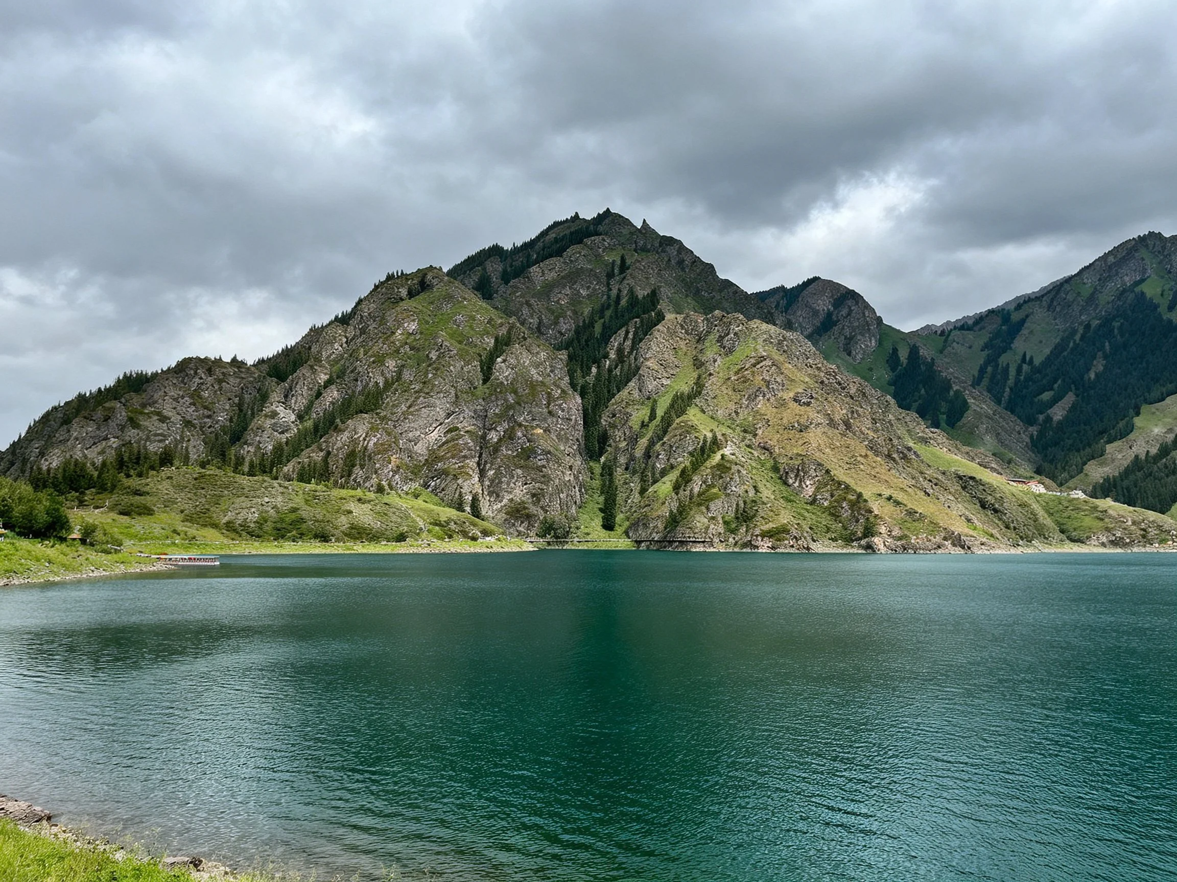 Turquoise Lake Among Lush Green Mountains Under Cloudy Sky