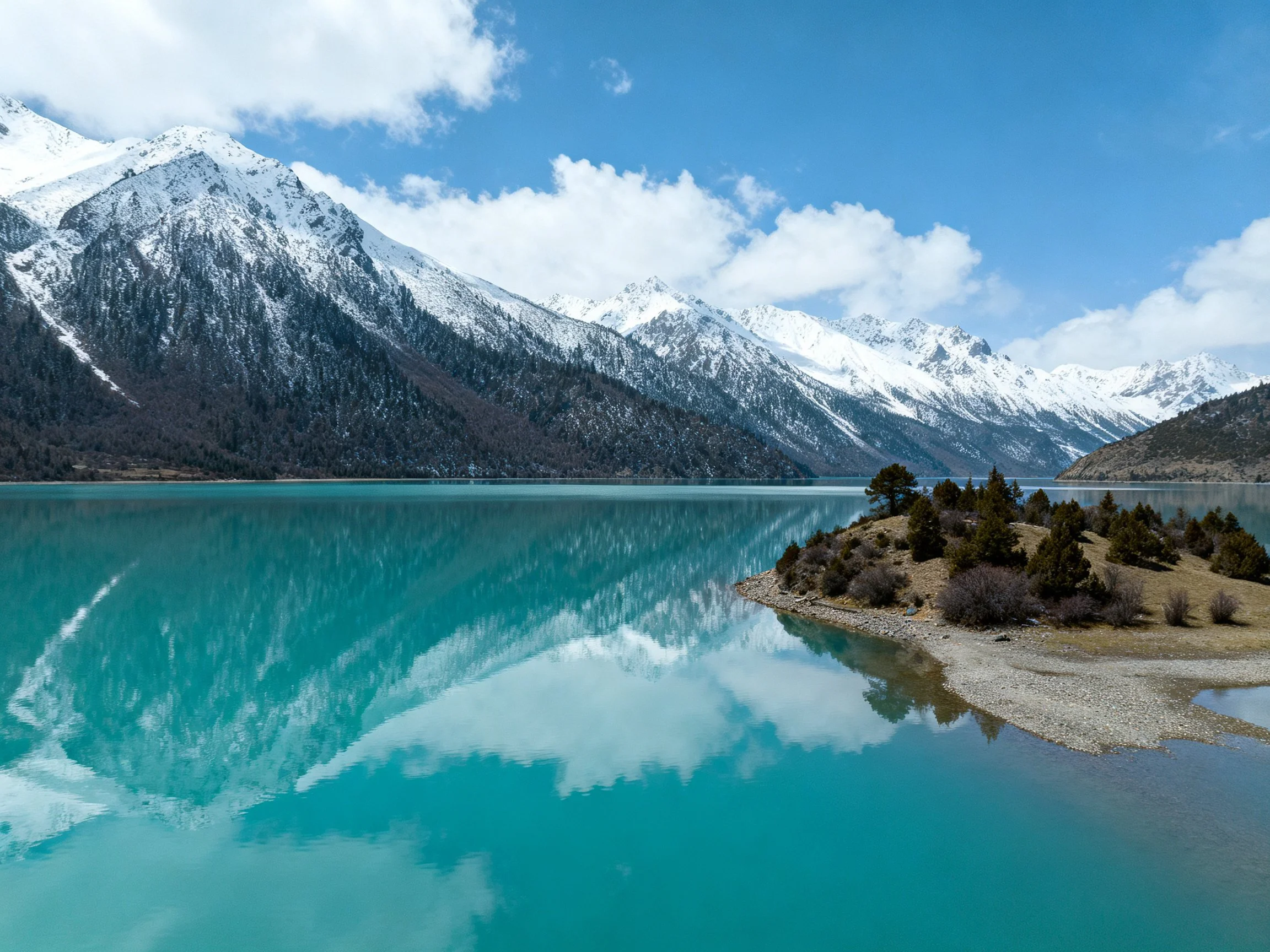 Turquoise Lake Reflects Snow-Capped Peaks and Blue Sky