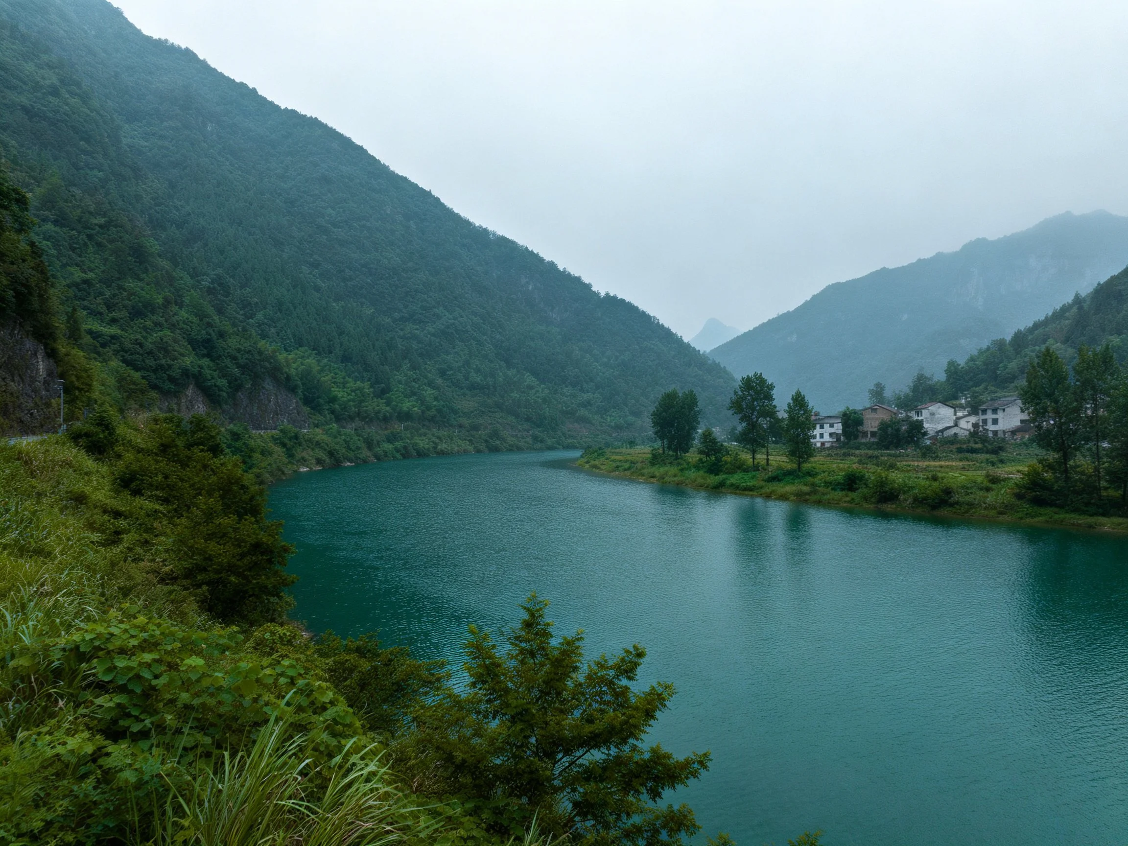 Turquoise River Flows Through Verdant Mountains Valley With Village