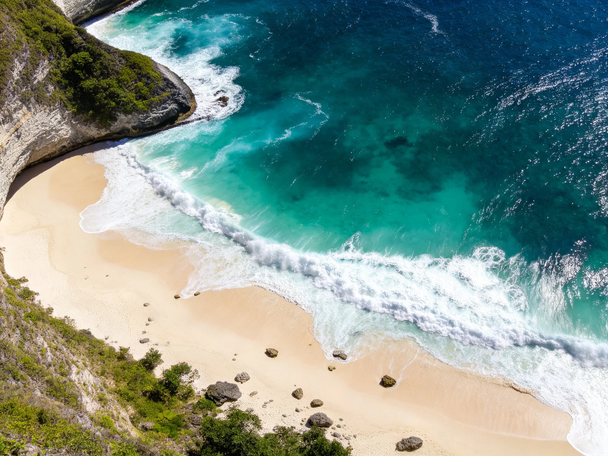 Turquoise ocean waves crash onto sandy shore near rocky cliffs