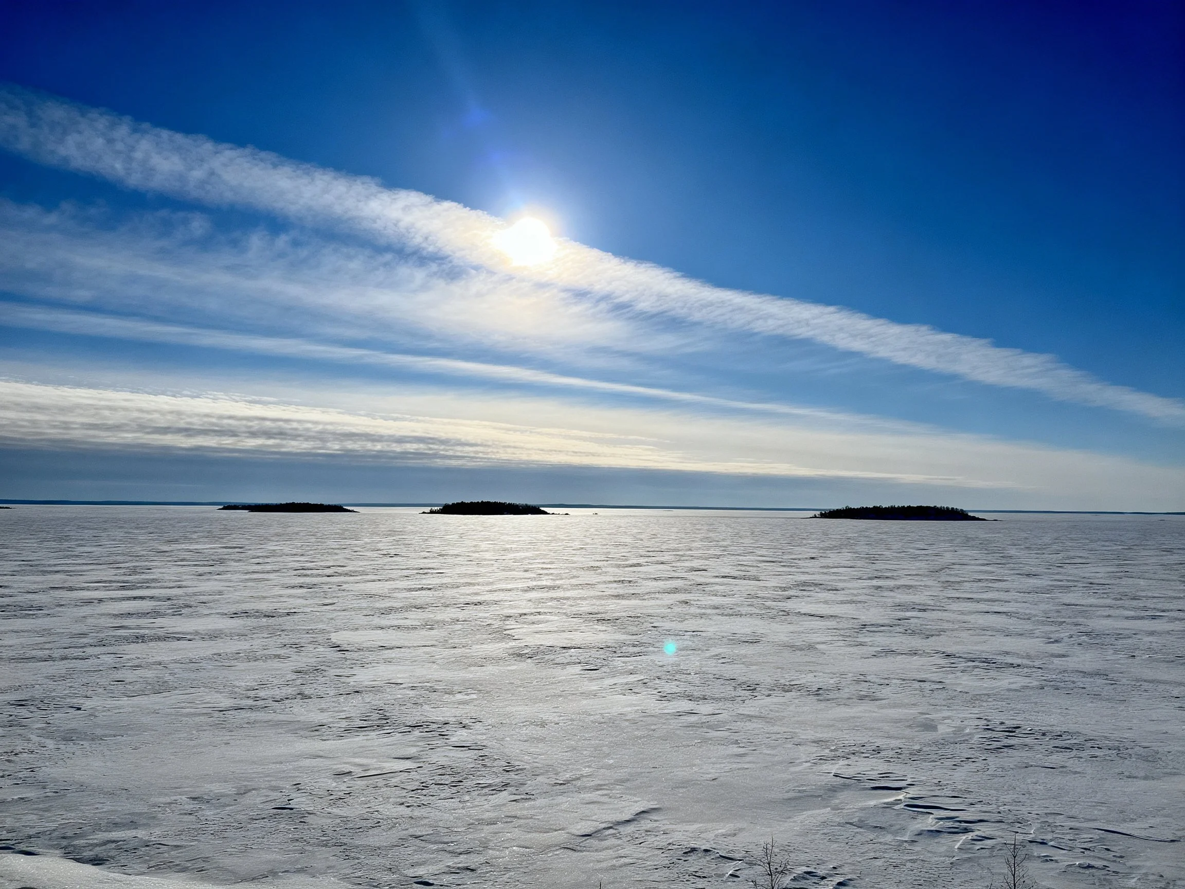 Vast frozen landscape with bright blue sky and distant islands