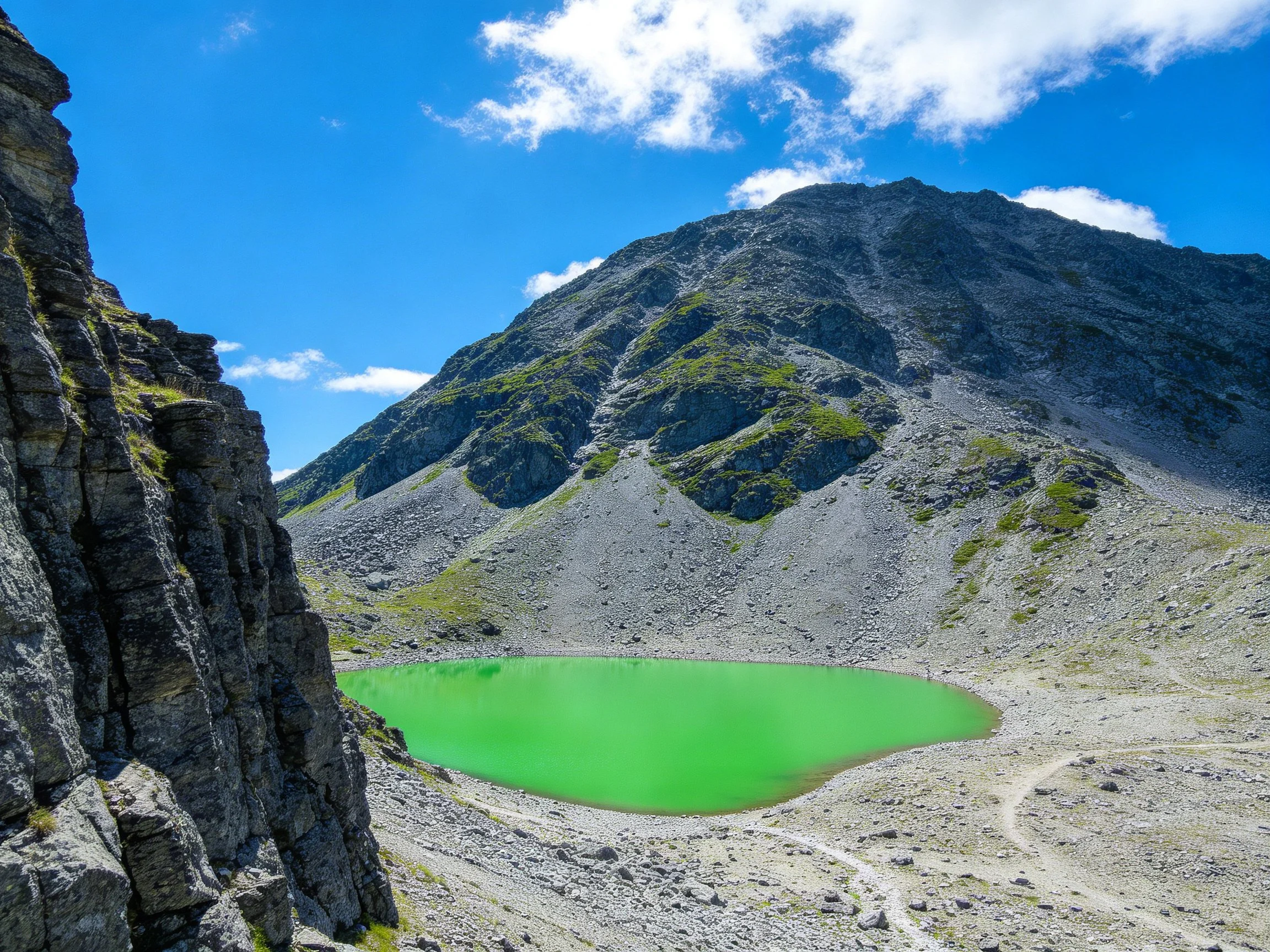 Vibrant Green Alpine Lake Among Rugged Gray Rocky Slopes