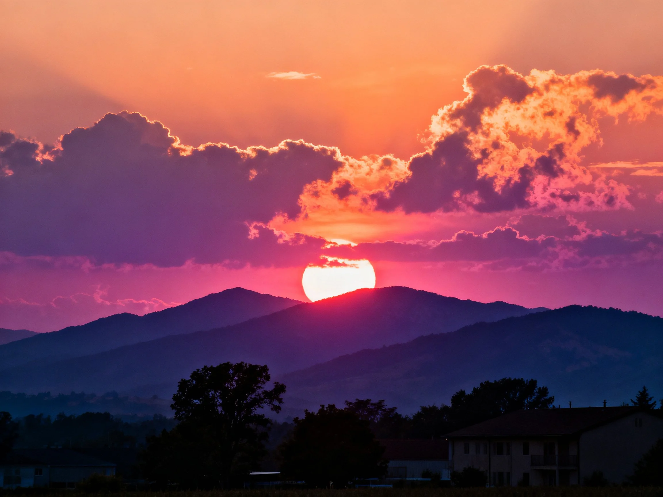 Vibrant Sunset Behind Mountain Peaks With Colorful Clouds
