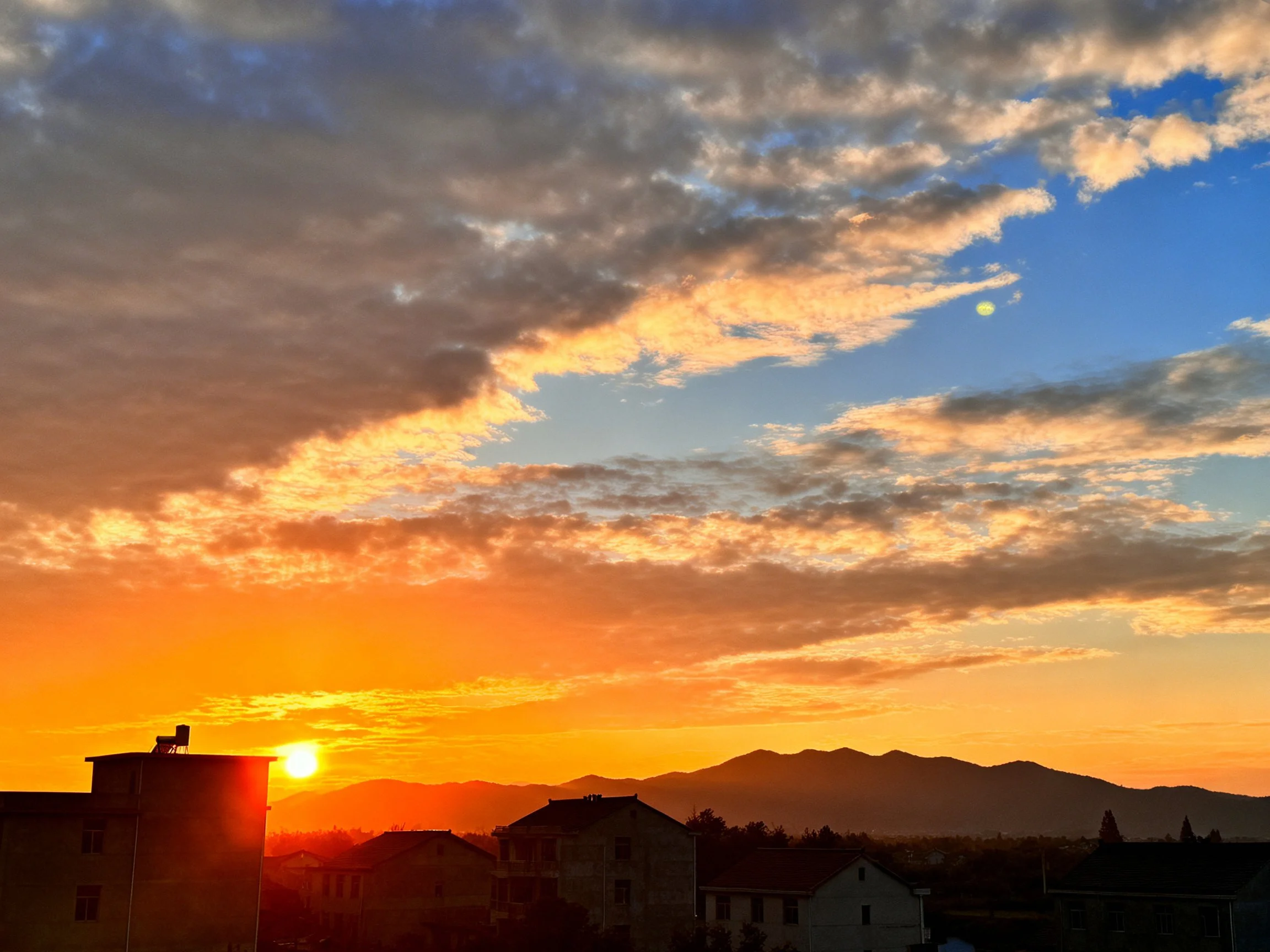 Vibrant Sunset Over Buildings and Mountains
