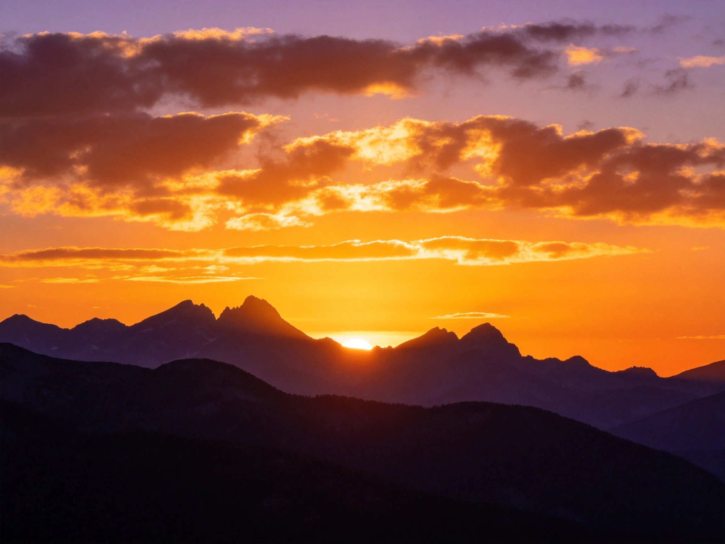 Vibrant Sunset Over Mountain Silhouettes with Colorful Clouds