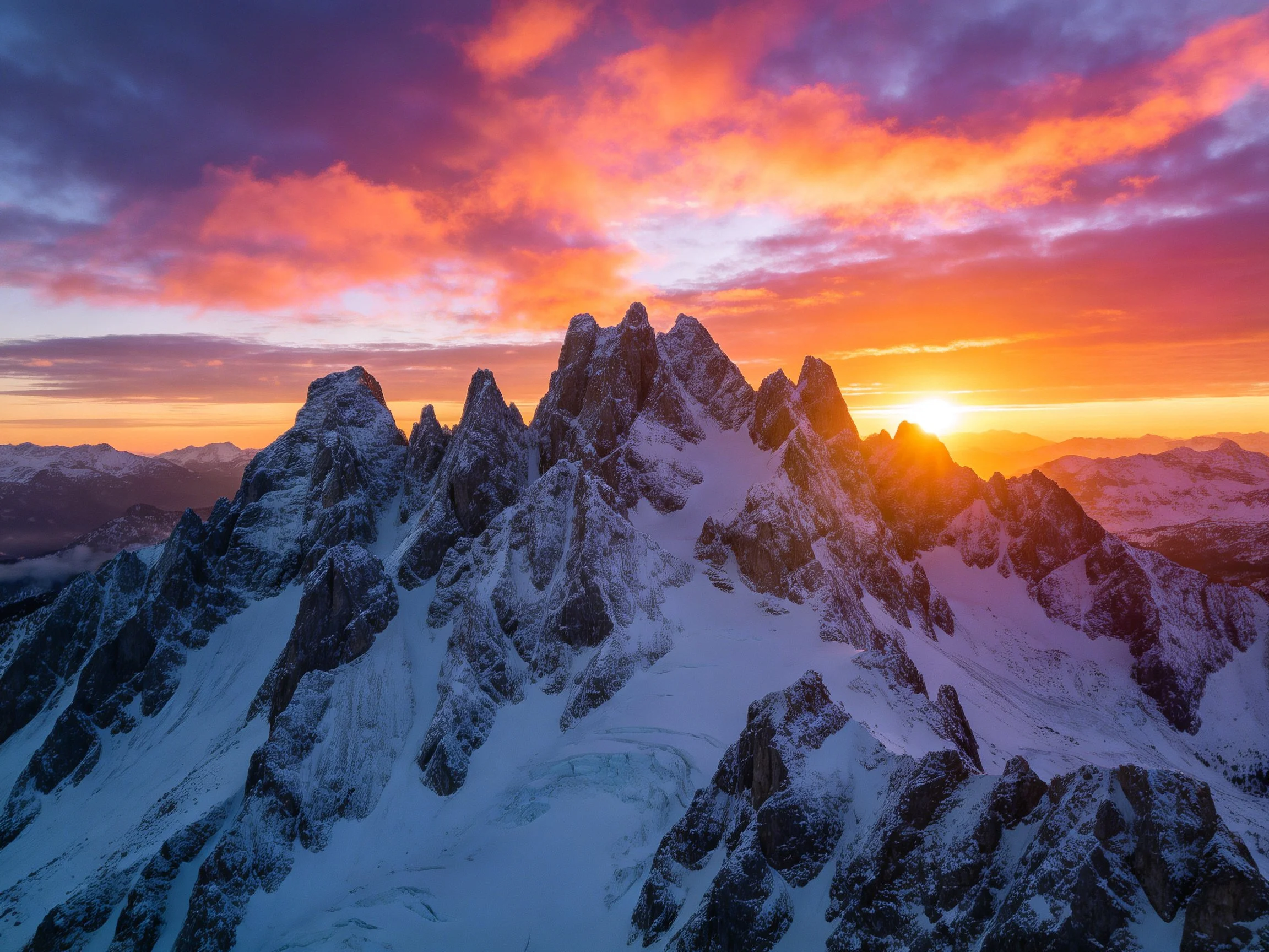 Vibrant Sunset Over Snow-Capped Jagged Peaks