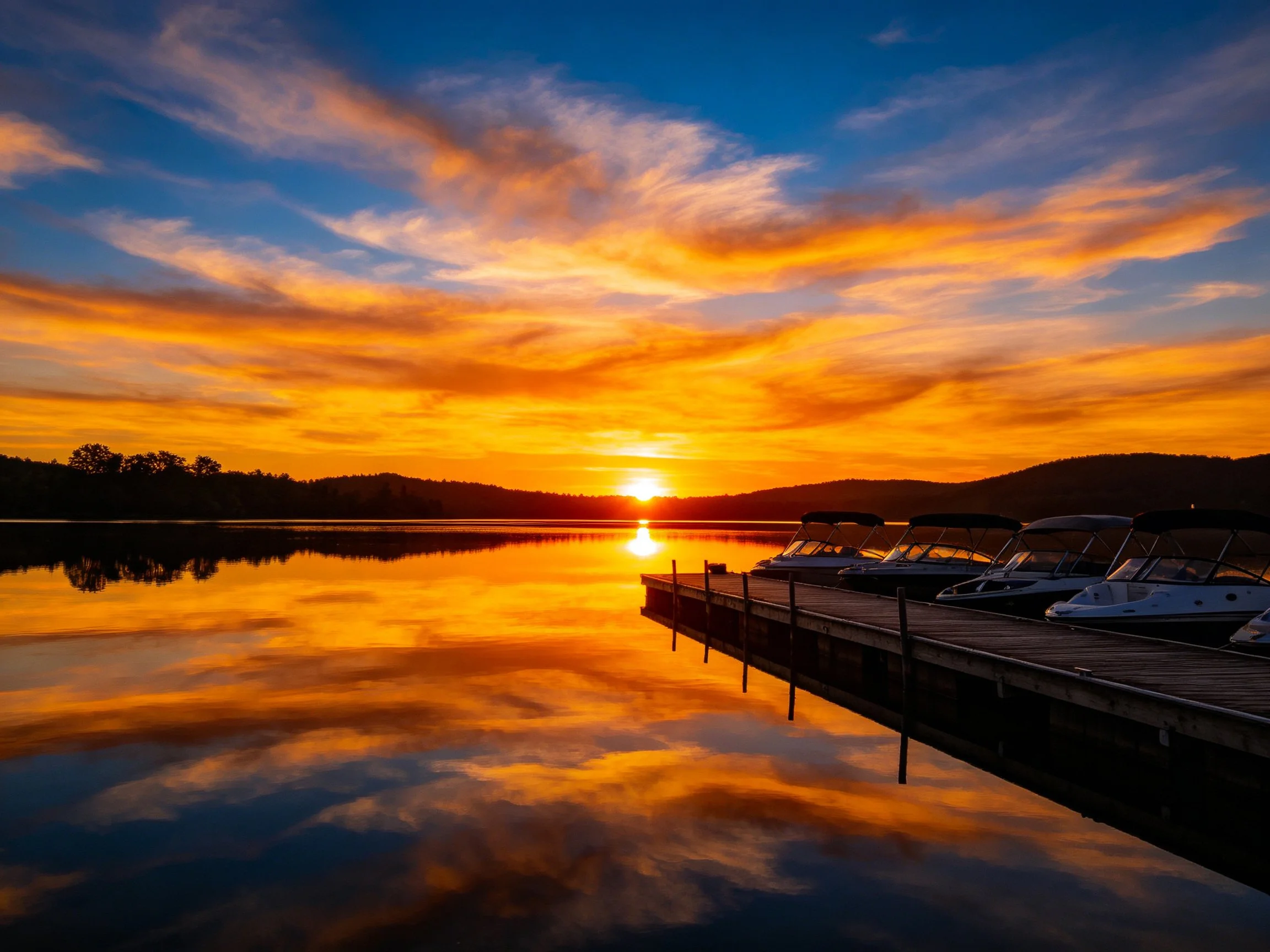 Vibrant Sunset Reflects on Calm Lake Near Dock