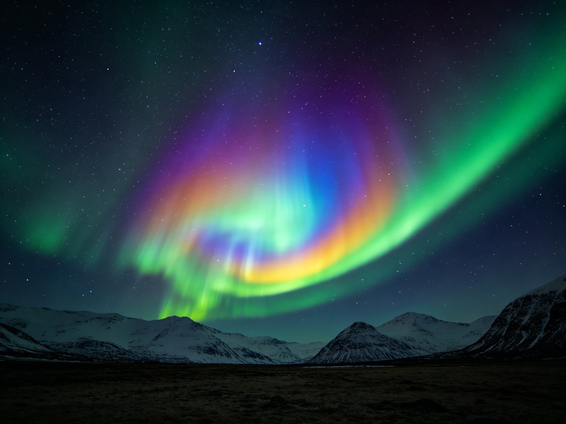 Vibrant aurora borealis illuminates snowy mountain landscape
